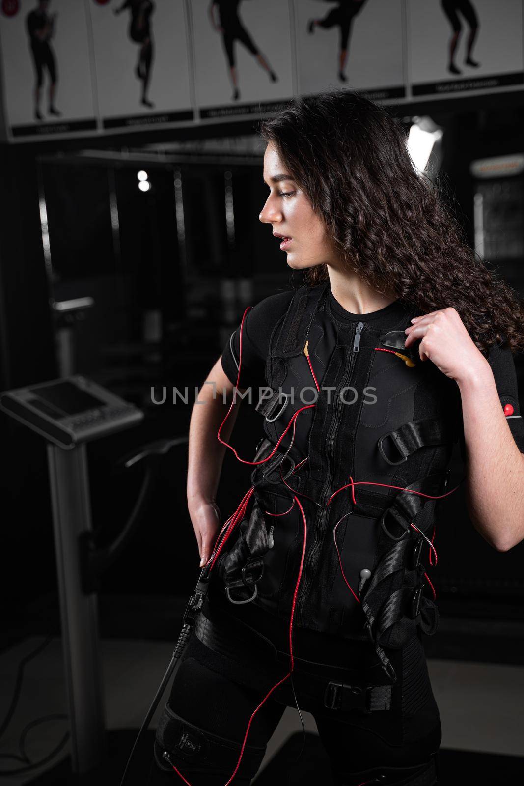 Girl in EMS suit in gym. Sport training in electrical muscle stimulation suit. by Rabizo