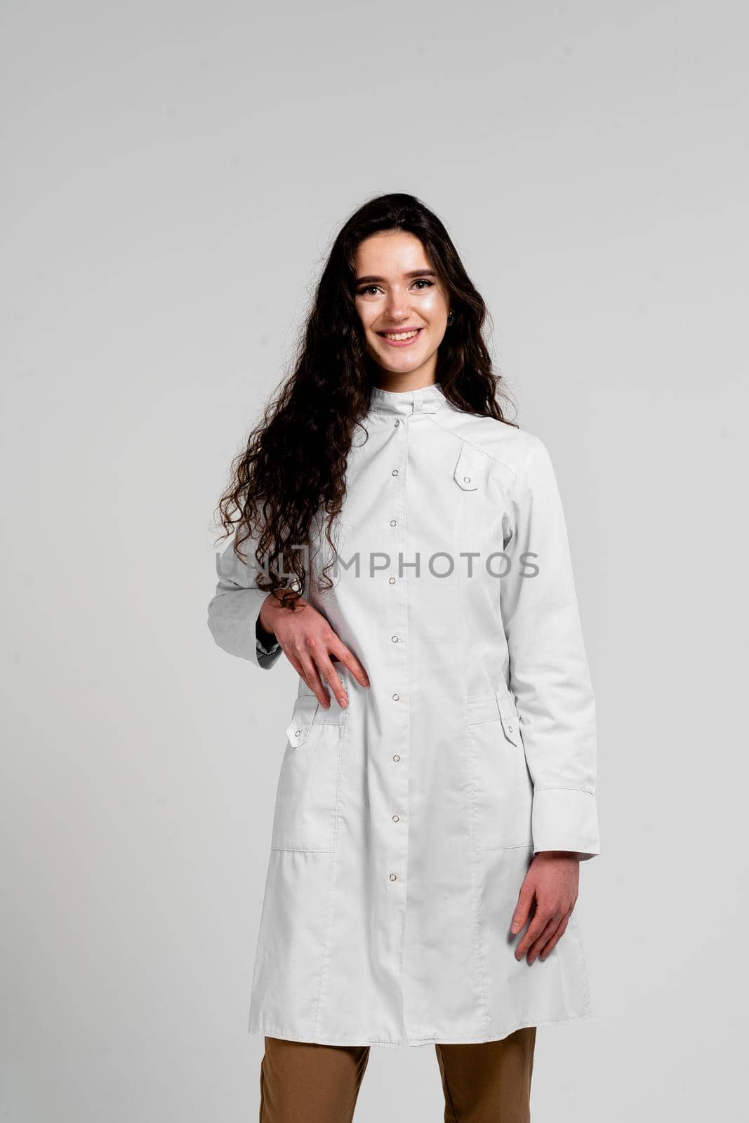 Girl surgeon in medical dress with curly hair on white background. 3rd wave of coronavirus covid-19 epidemy by Rabizo