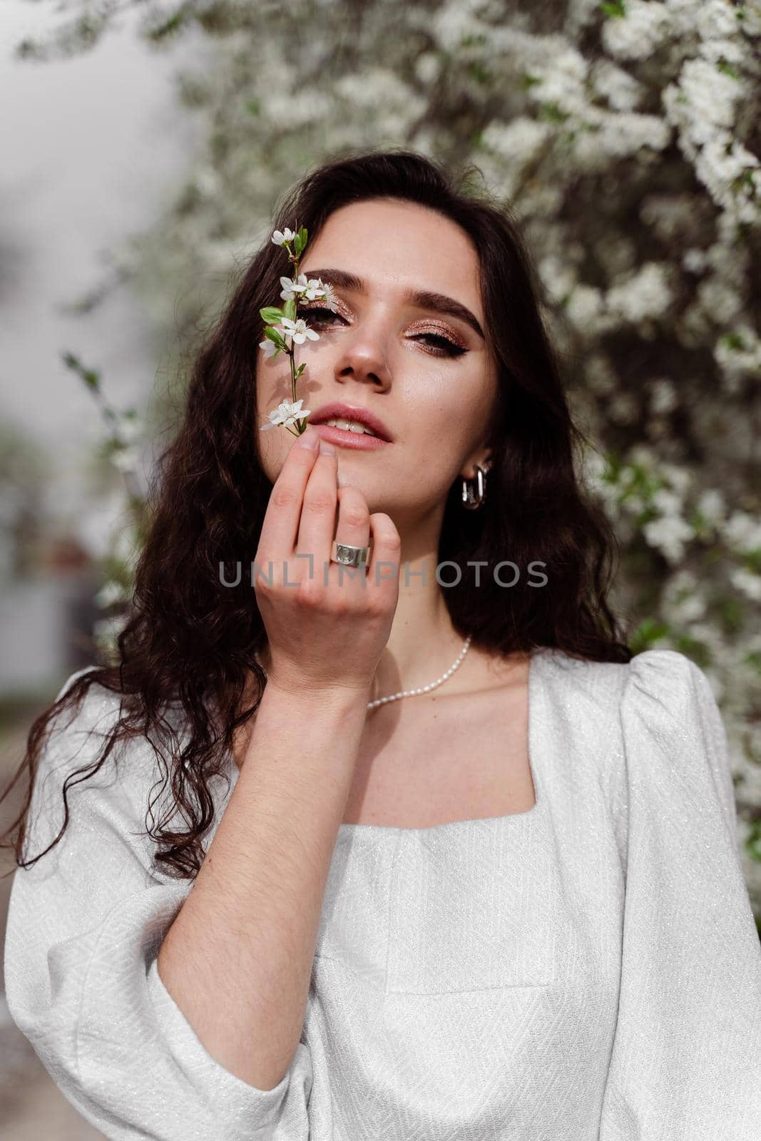 Lovely girl near blooming trees in the park. Outdoor walking in at sunny day. Lifestyle of young woman