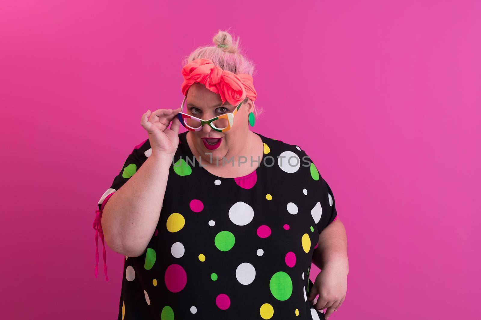 Happy Plus Size Woman Wearing Eyeglasses Smiling To Camera Standing Over Pink Background. Cheerful Millennial Female In Eyewear Posing In Studio. High quality photo