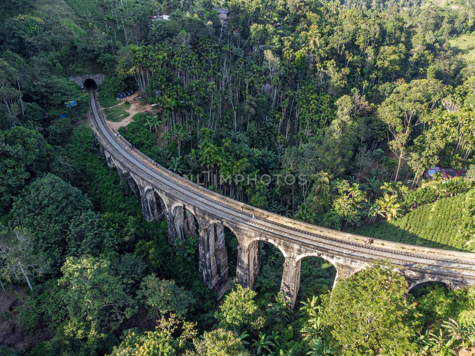 Sri Lanka. The attraction is the ancient railway Nine-arch Demodara Bridge in the midst of a dense tropical forest. Shooting from the air on a drone. Sunny day, sunset.