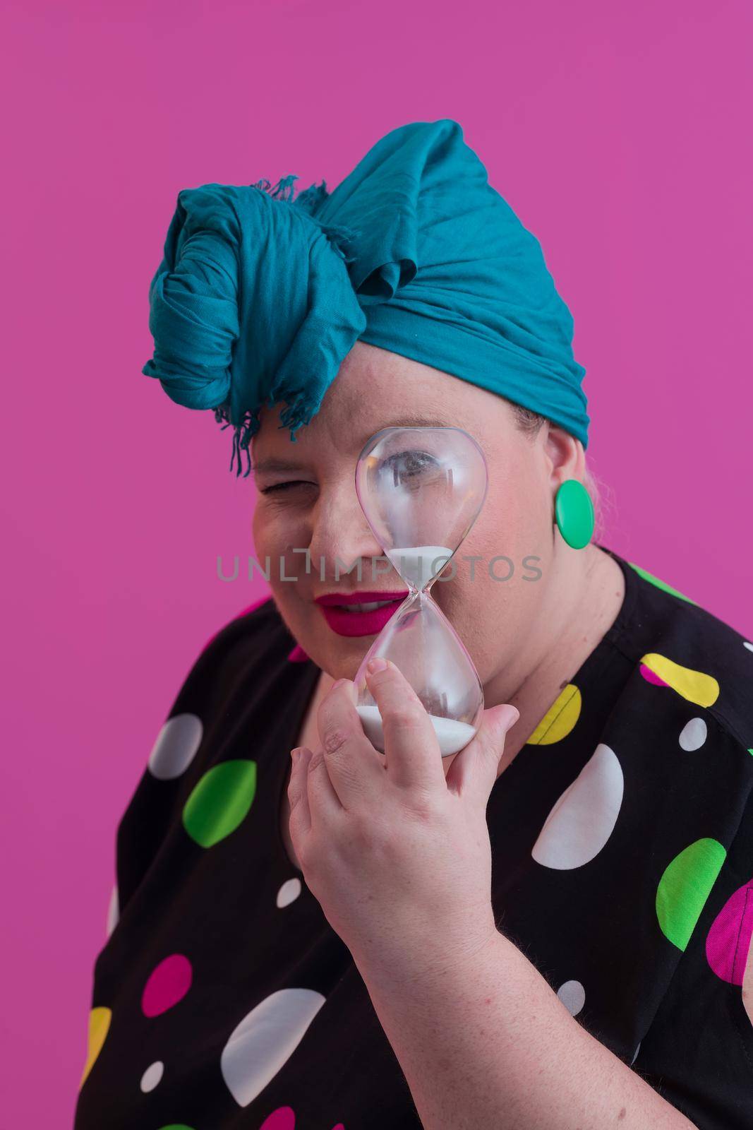 Portrait of plus size young lady smiling hands holds sand clock isolated on pink color background. High quality photo