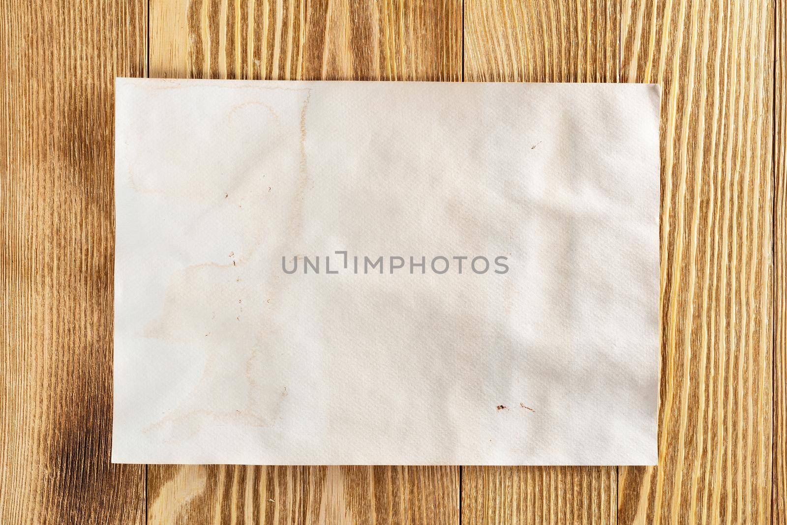 Minimal wooden desk workplace with blank paper. Flat lay textured natural wooden background. Vintage copy space for creative design and advertising. Close up A4 format paper on wooden surface.