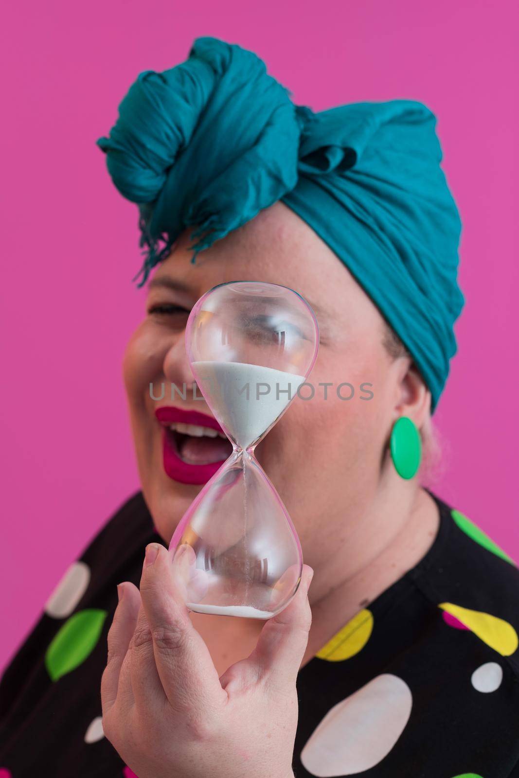 Portrait of plus size young lady smiling hands holds sand clock isolated on pink color background. High quality photo