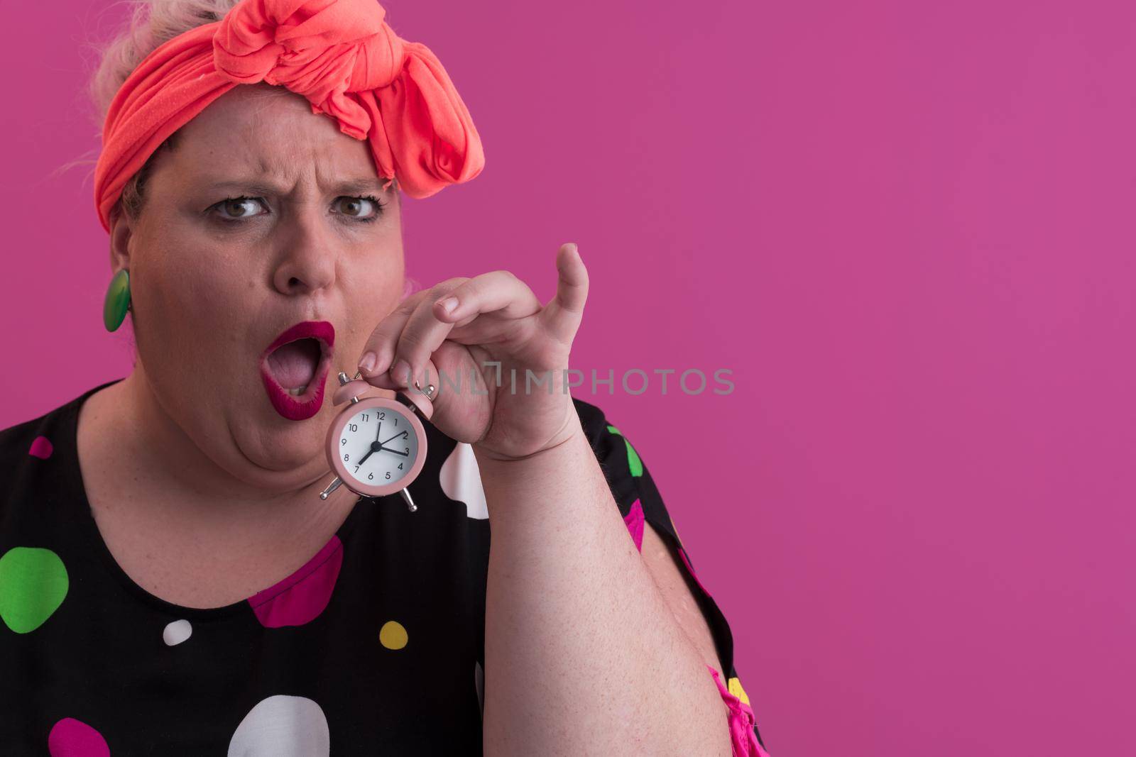 Portrait of plus size young lady smiling hands holds sand clock isolated on pink color background. High quality photo