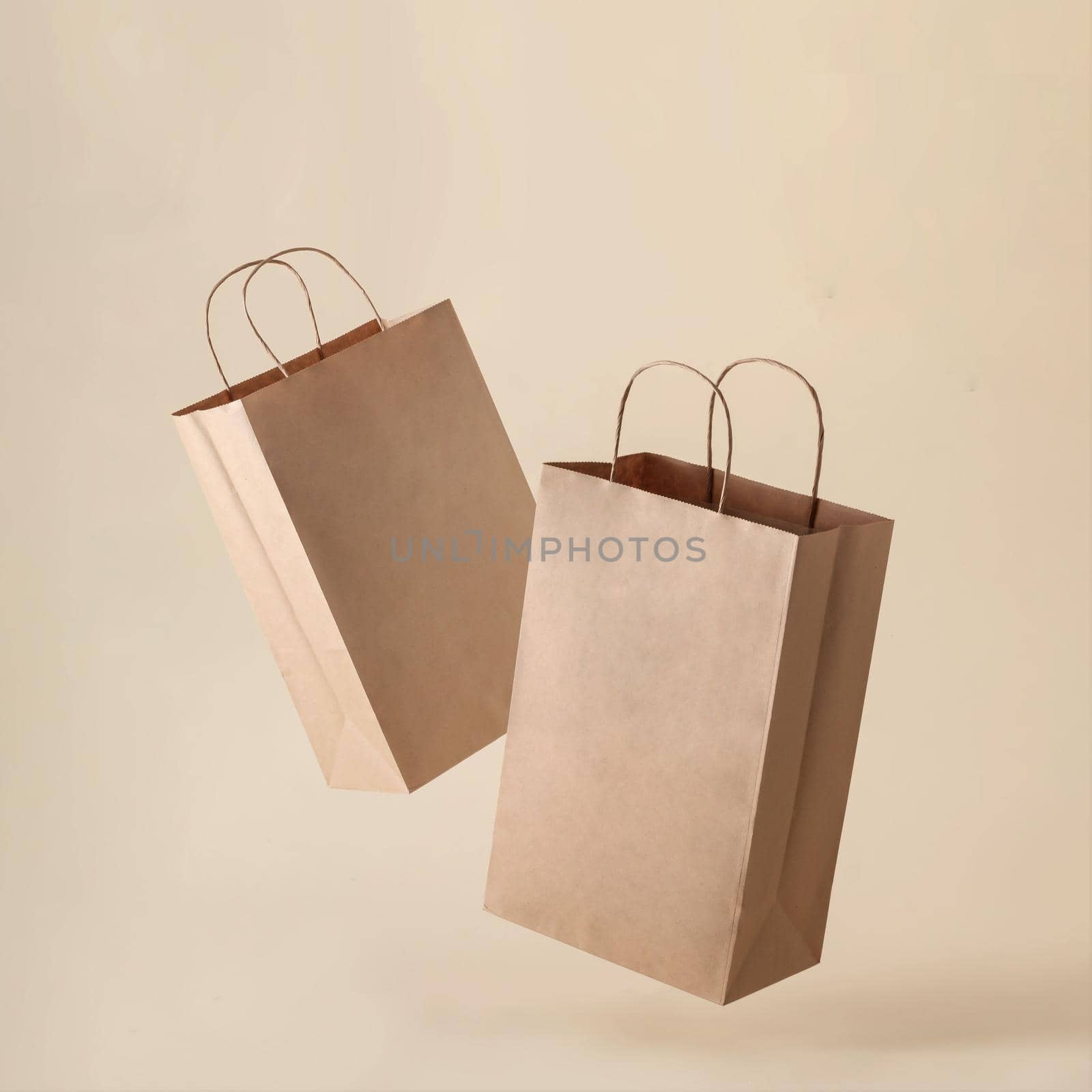 Two paper bags in a container levitation on a clean beige background by sergii_gnatiuk