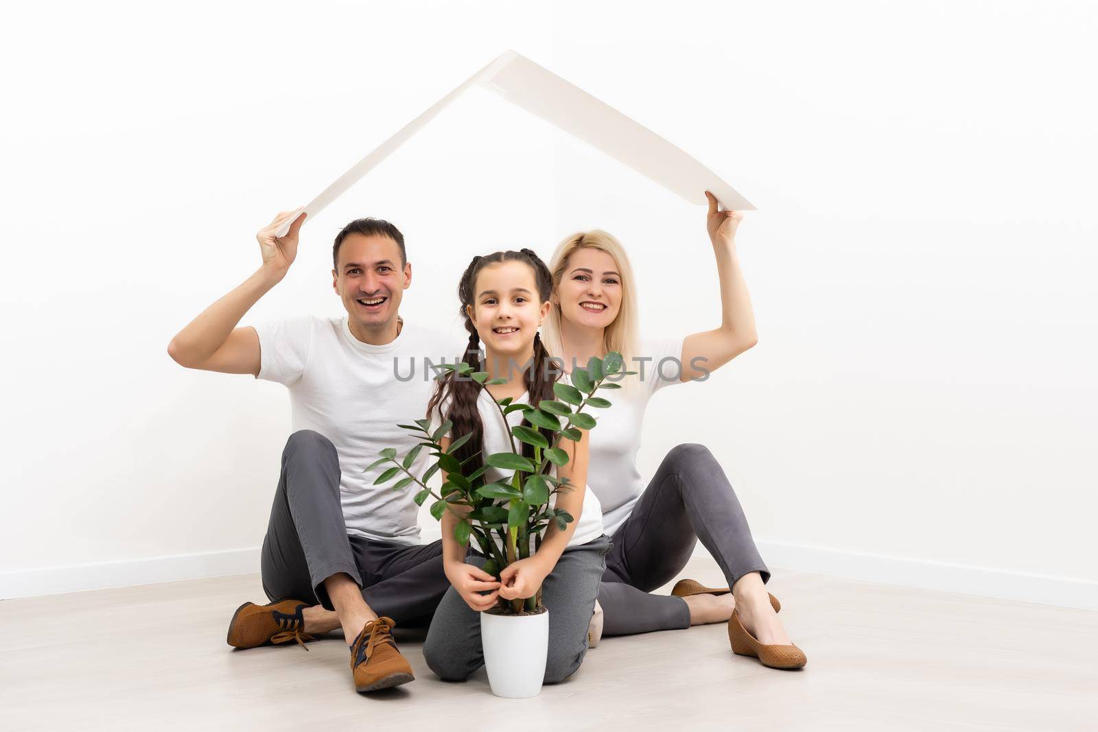 Photo of adorable caucasian family woman and man with little girl smiling and posing together at camera over white background.