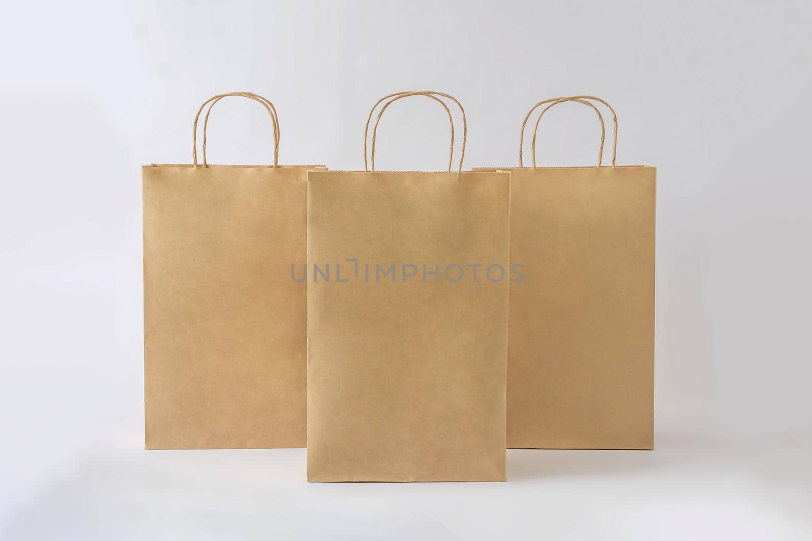 Three cardboard bags in a row on a white background as a business or delivery mockup. Concept of buy sell and recycling.