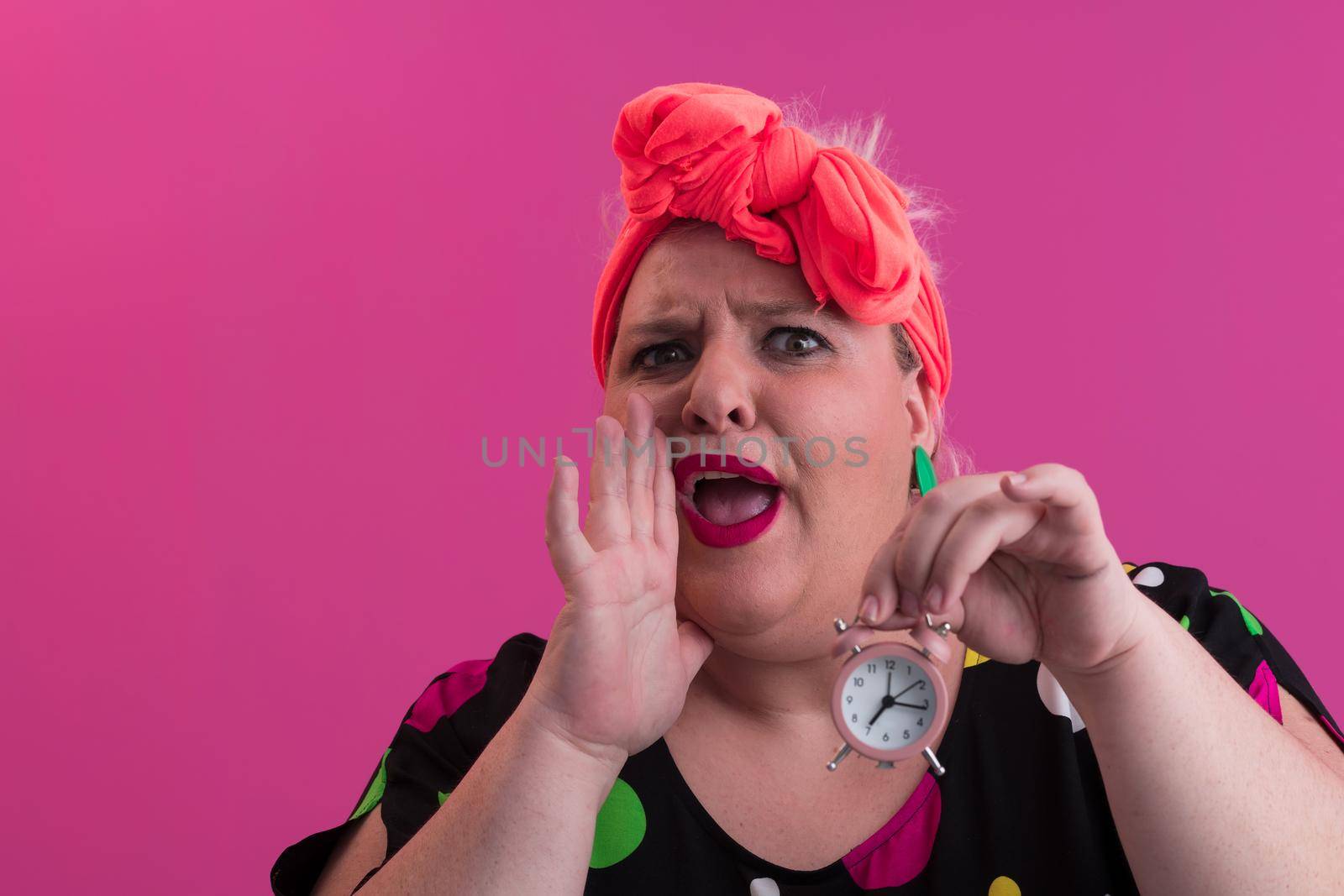 Portrait of plus size young lady smiling hands holds sand clock isolated on pink color background. High quality photo