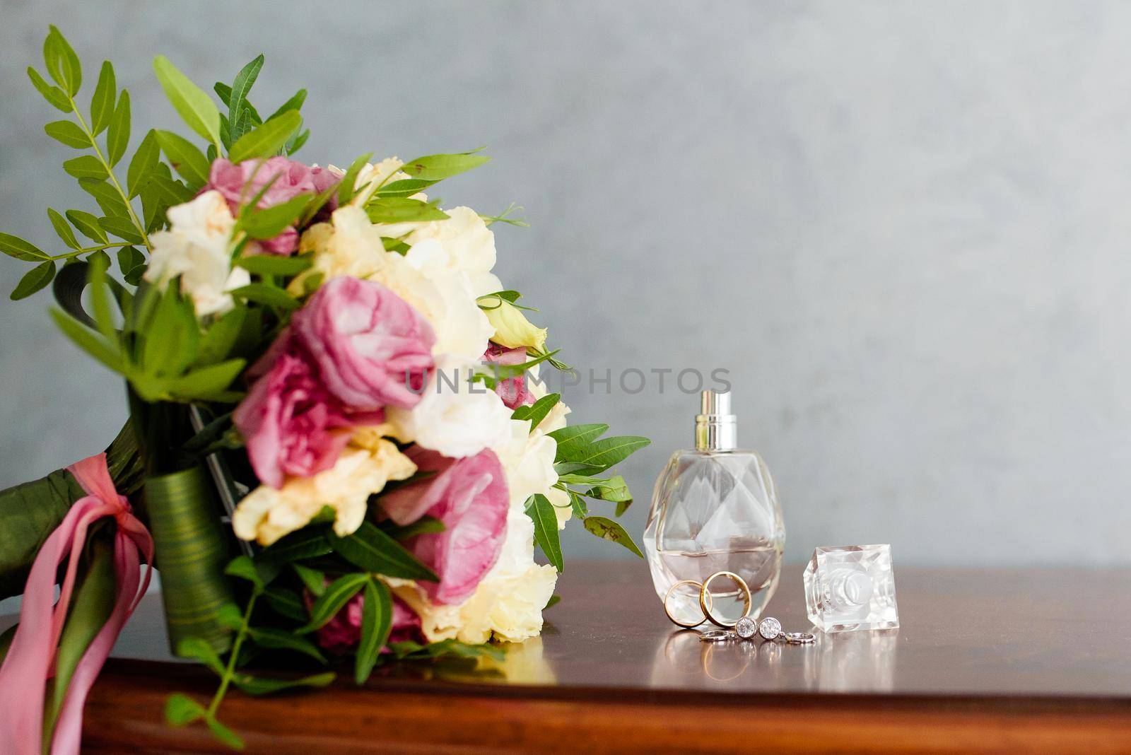 Wedding rings with perfume and a wedding bouquet on the nightstand. Wedding symbols, attributes.
