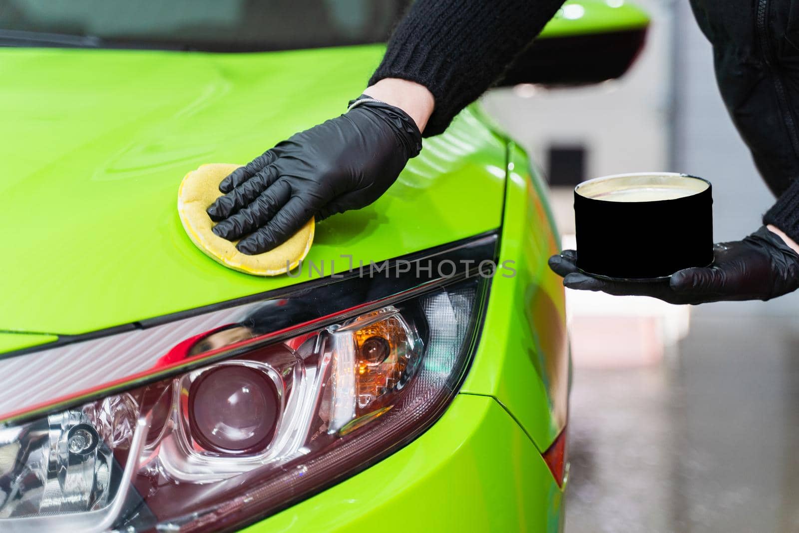 Hard wax for protection paintwork of car using sponge for remove paint scratches. Applying hard wax with a yellow sponge. Protection of paintwork by Rabizo