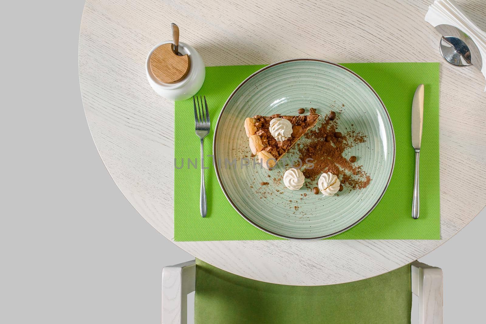 A piece of chocolate cake decorated with meringues, coffee beans and biscuit crumbs, cappuccino. Dessert tiramisu, top view.