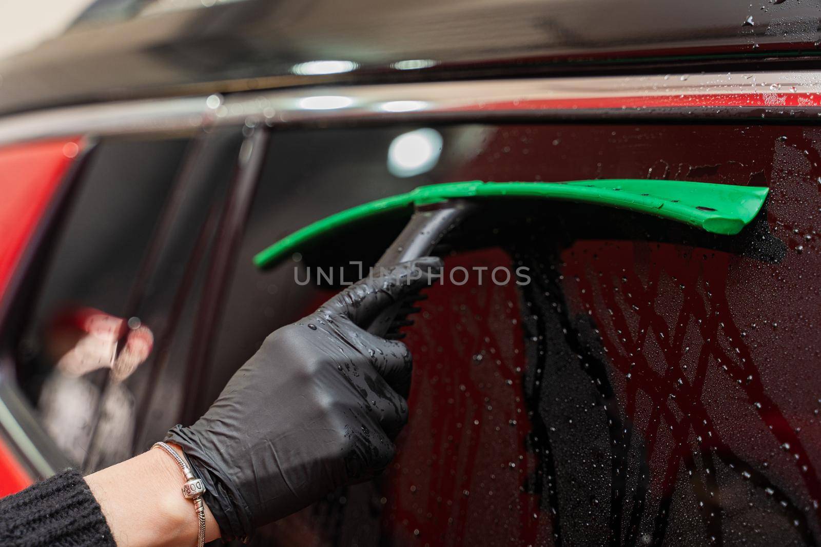 Removal of water from the glass with a rubber scraper after washing the car. Car Wash. Self-service complex. High-pressure car wash.