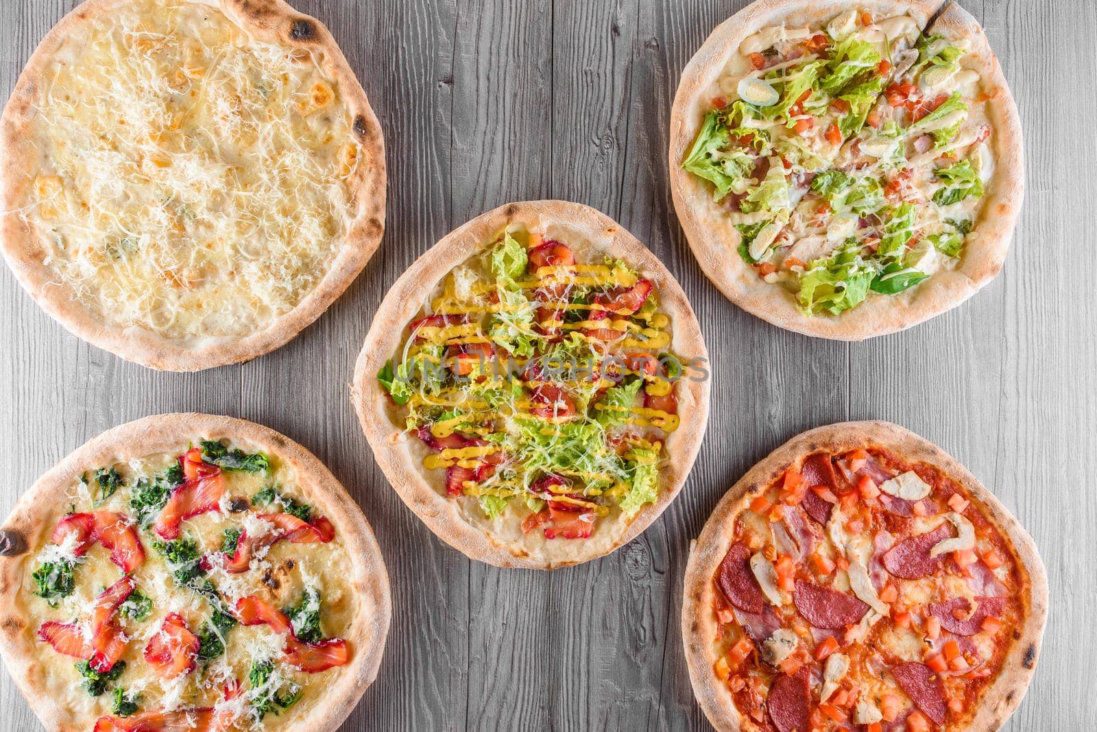 Assortment of pizza with meat, salami, prosciutto, tomatoes, dorblu cheese, mozzarella, parmesan and salad, spinach, red fish on wooden boards. Four cheese pizza, caesar, top view, by Rabizo