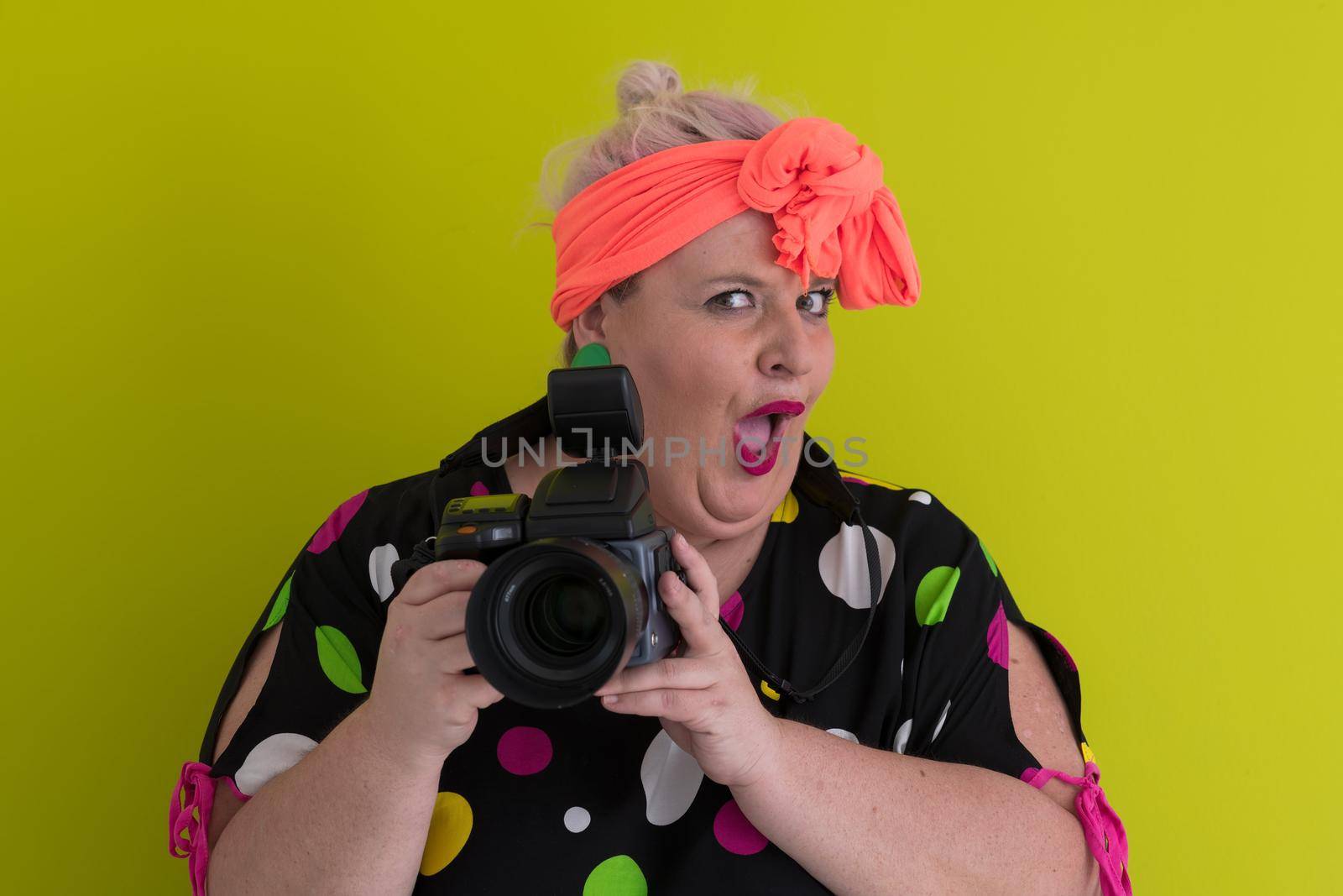 plus size smiling woman with funny emotional face expression with vintage camera in dress isolated on green background, traveler on vacation, summer fashion style, excited tourist. High quality photo