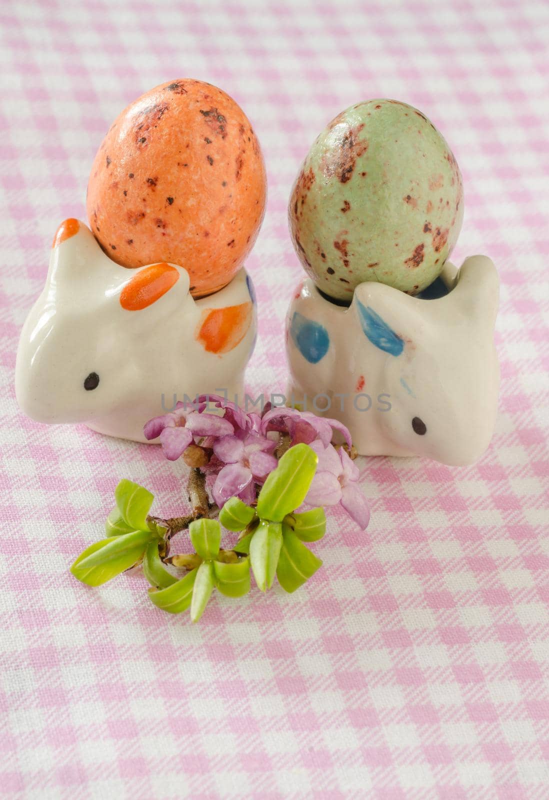 Two porcelain rabbit with eggs and small bouquet of beautiful flowers. Easter still life.