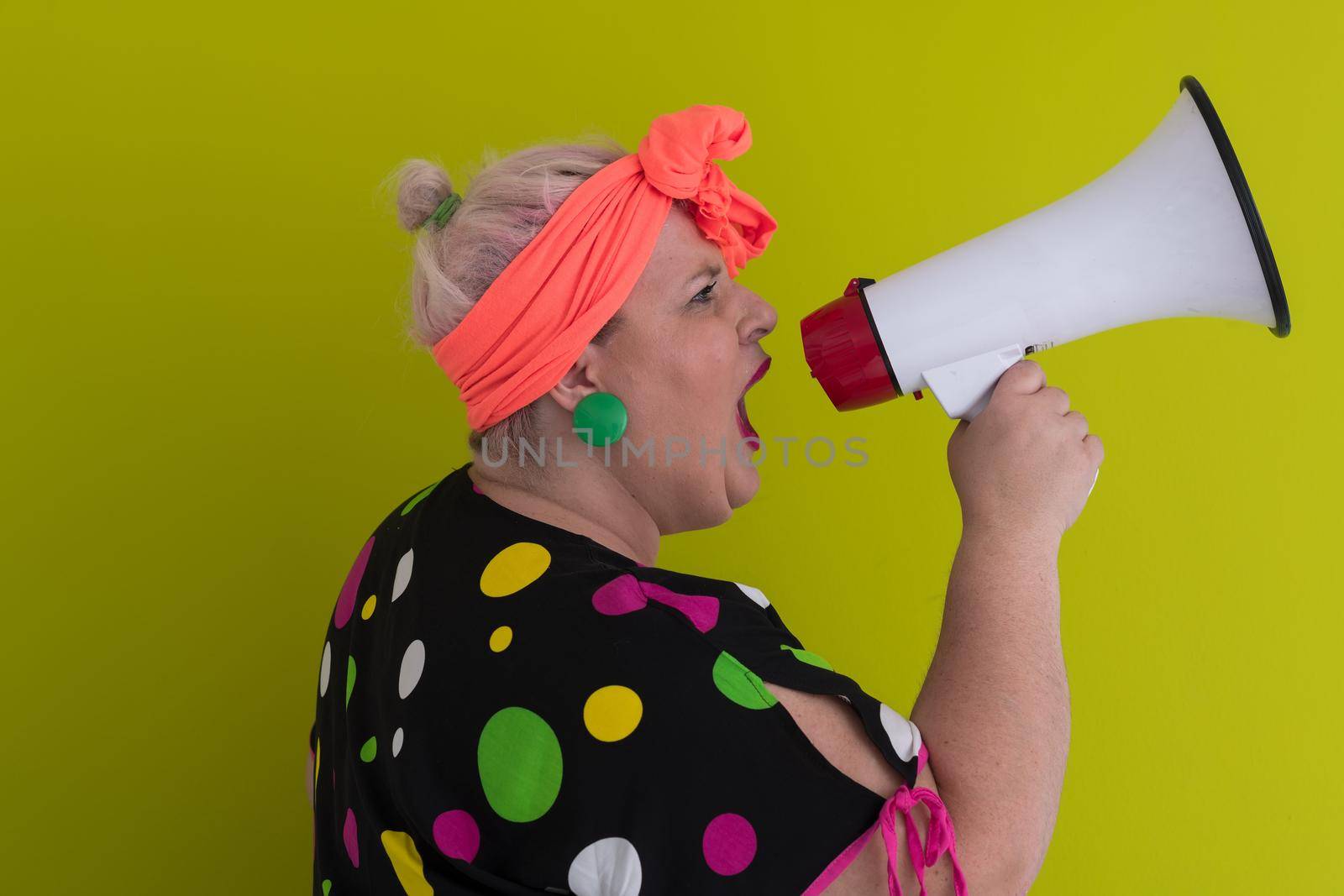 Funny plus size woman woman posing isolated on pastel green background studio portrait. People emotions lifestyle concept. Mock up copy space. Screaming in megaphone. High quality photo