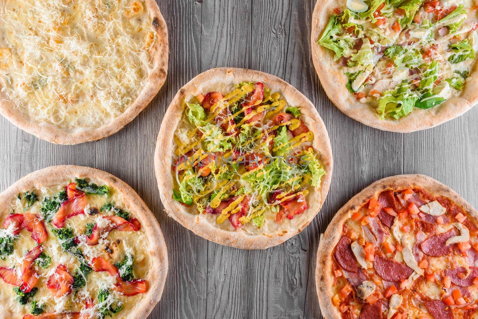 Assortment of pizza with meat, salami, prosciutto, tomatoes, dorblu cheese, mozzarella, parmesan, salad, spinach, red fish on wooden boards. Four cheese pizza, caesar, top view.