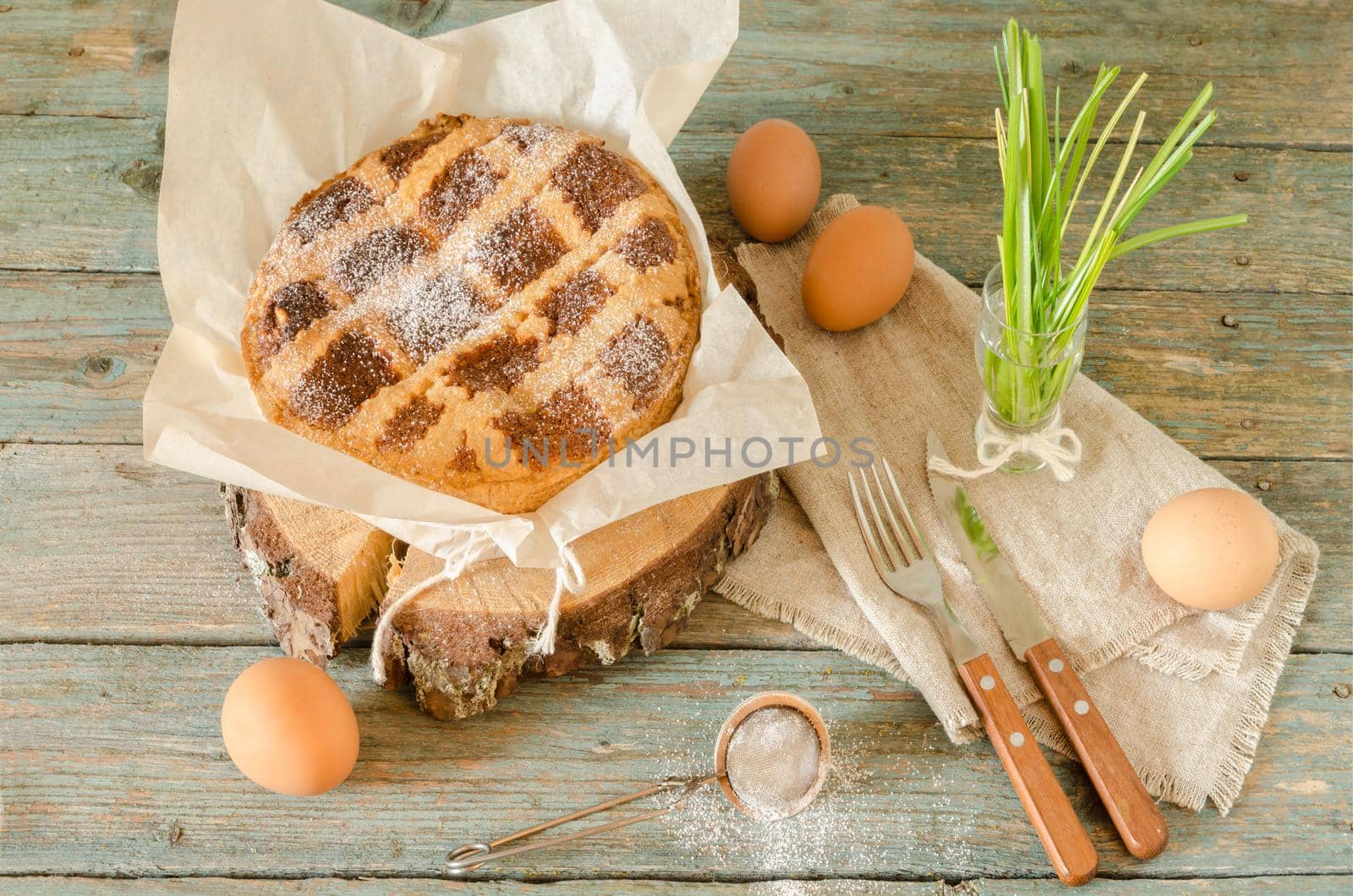 Neapolitan Easter cake with ricotta and wheat on old wooden table. Next egg, knife and fork. Rustic style.