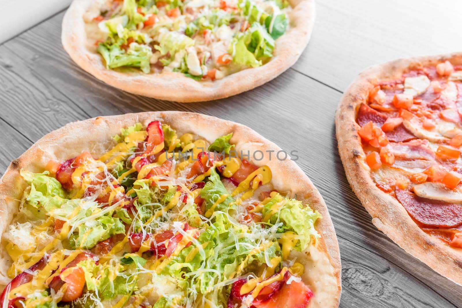 Assortment of pizza with meat, salami, prosciutto, tomatoes, dorblu cheese, mozzarella, parmesan and salad, spinach, red fish on wooden boards. Four cheese pizza, caesar, top view by Rabizo