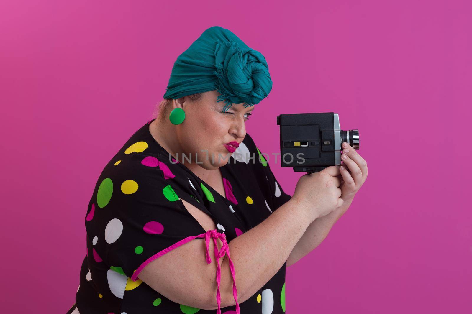 plus size smiling woman with funny emotional face expression with vintage camera in dress isolated on pink background, traveler on vacation, summer fashion style, excited tourist. High quality photo