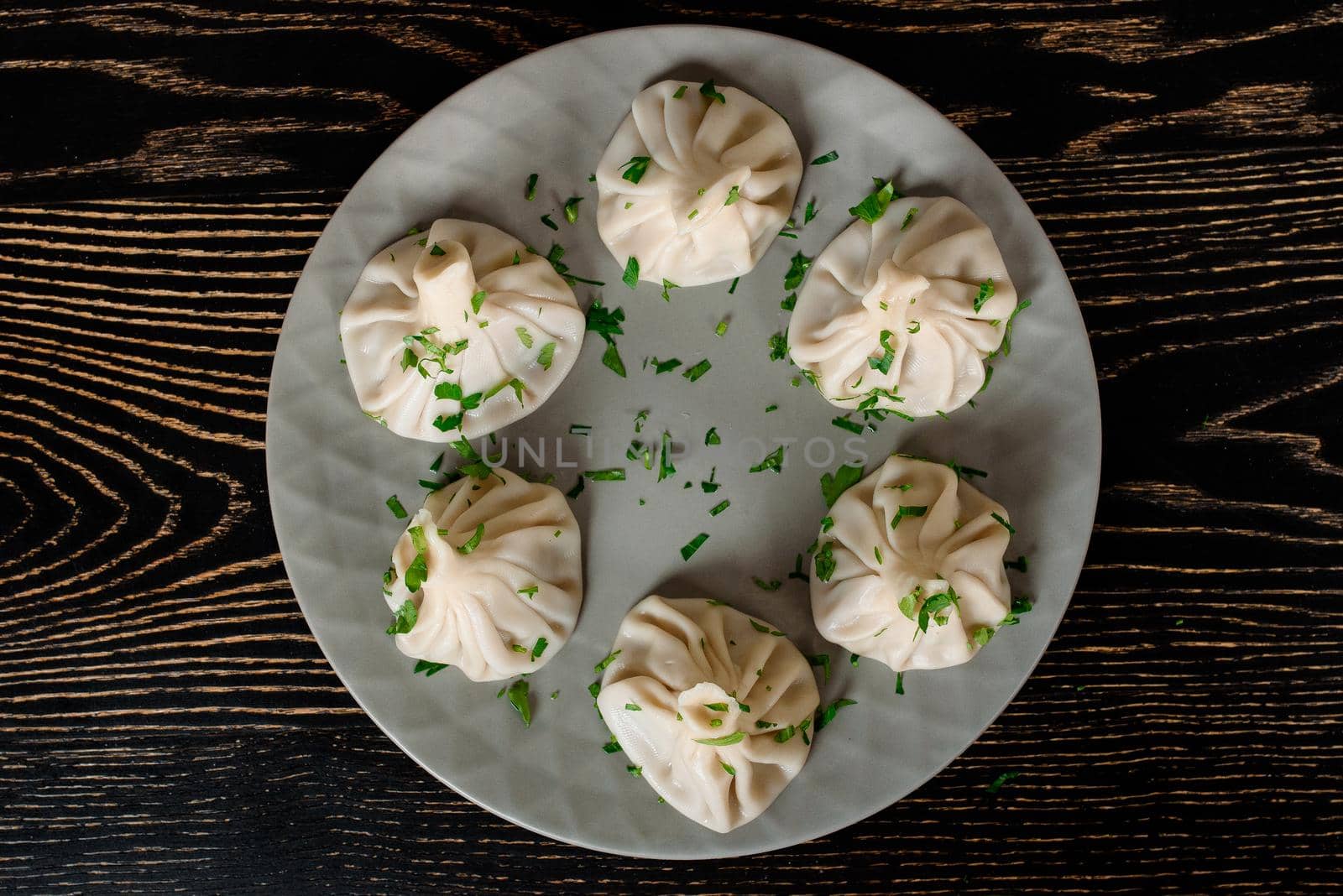 Khinkali traditional Georgian cuisine decorated with cilantro on a gray plate. Top view. by Rabizo