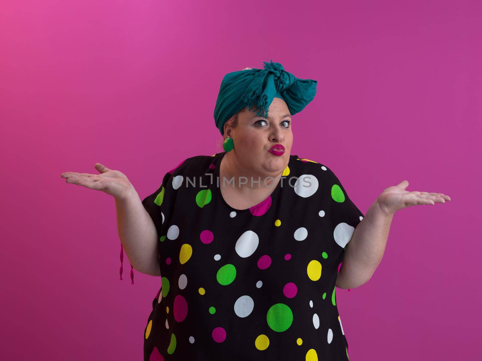 Plus size sexy model woman with trendy makeup, fashionable blonde in black short dress posing at the pink background in studio. High quality photo