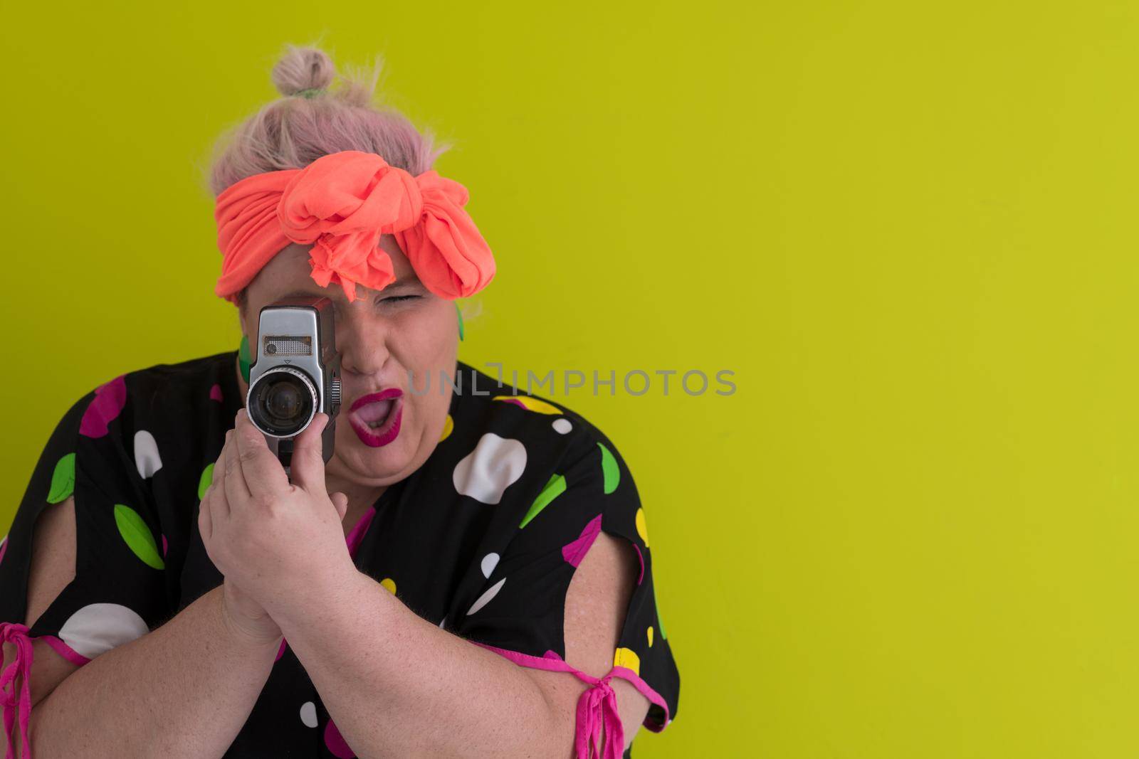 plus size smiling woman with funny emotional face expression with vintage camera in dress isolated on green background, traveler on vacation, summer fashion style, excited tourist. High quality photo