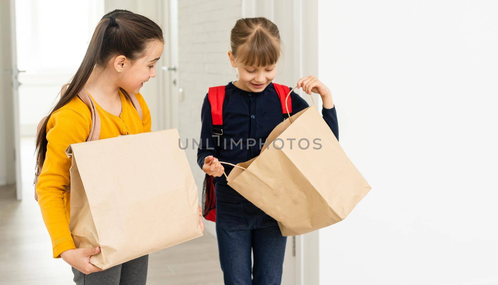two school girls with backpack and delivery packages hands in white background.