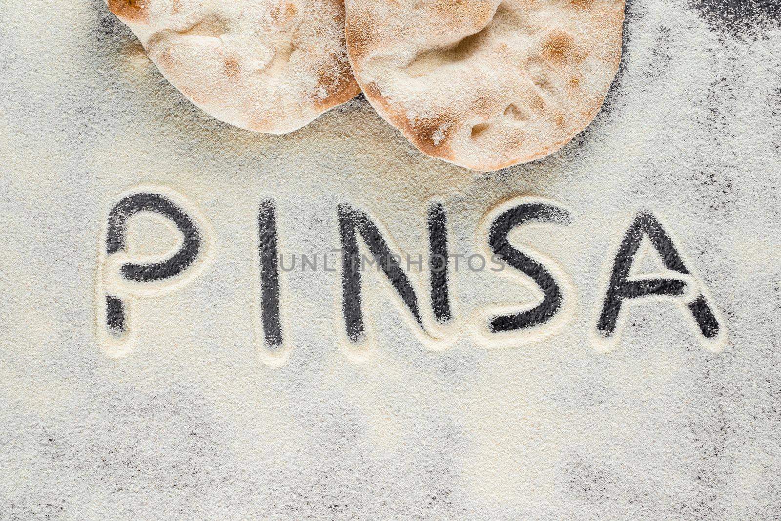 Dough and flour with text pinsa on black background. Pinsa romana and scrocchiarella gourmet italian cuisine. Traditional dish in italy