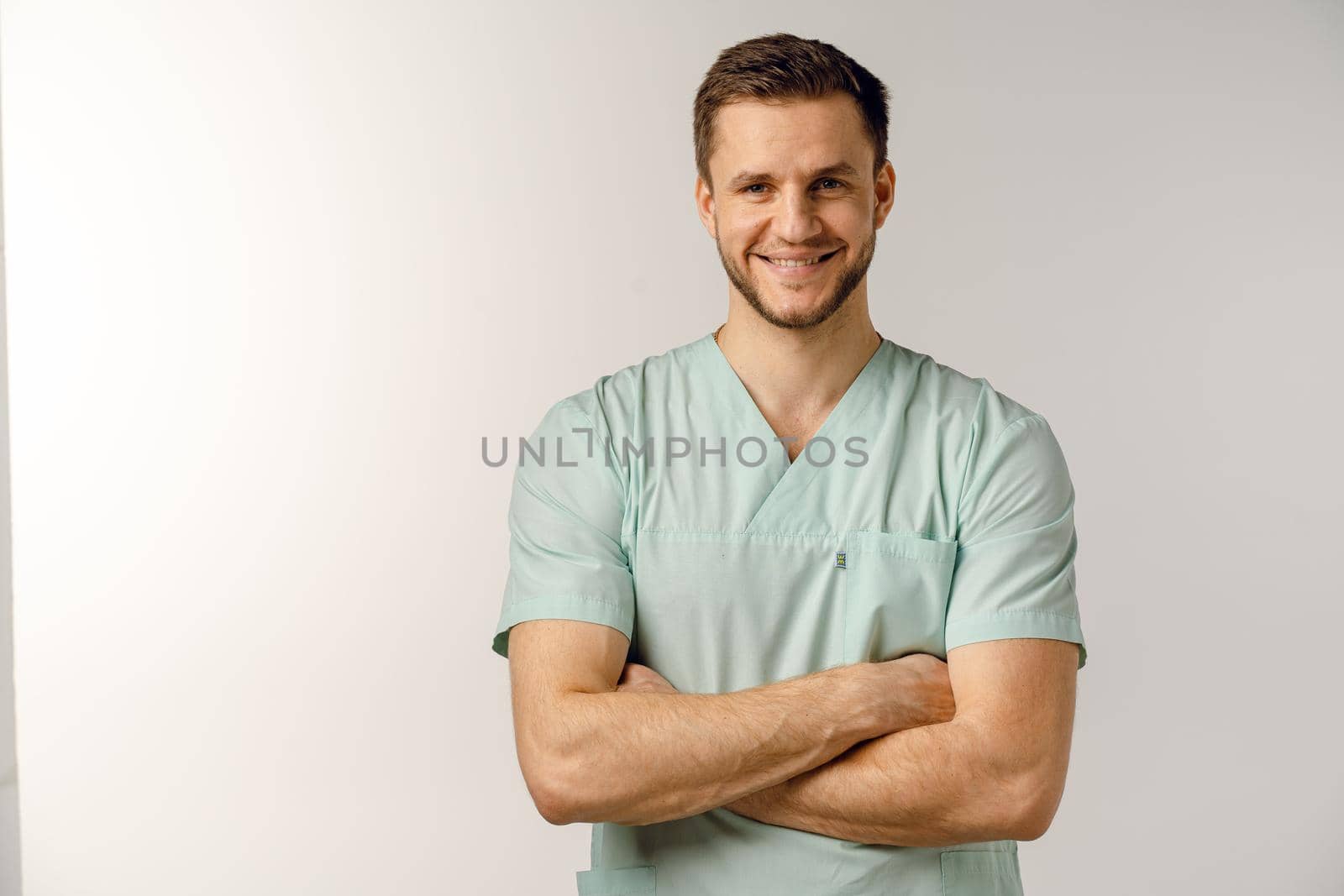 Surgeon weared in medical robe smile and posing on white background. Handsome happy doctor posing in studio