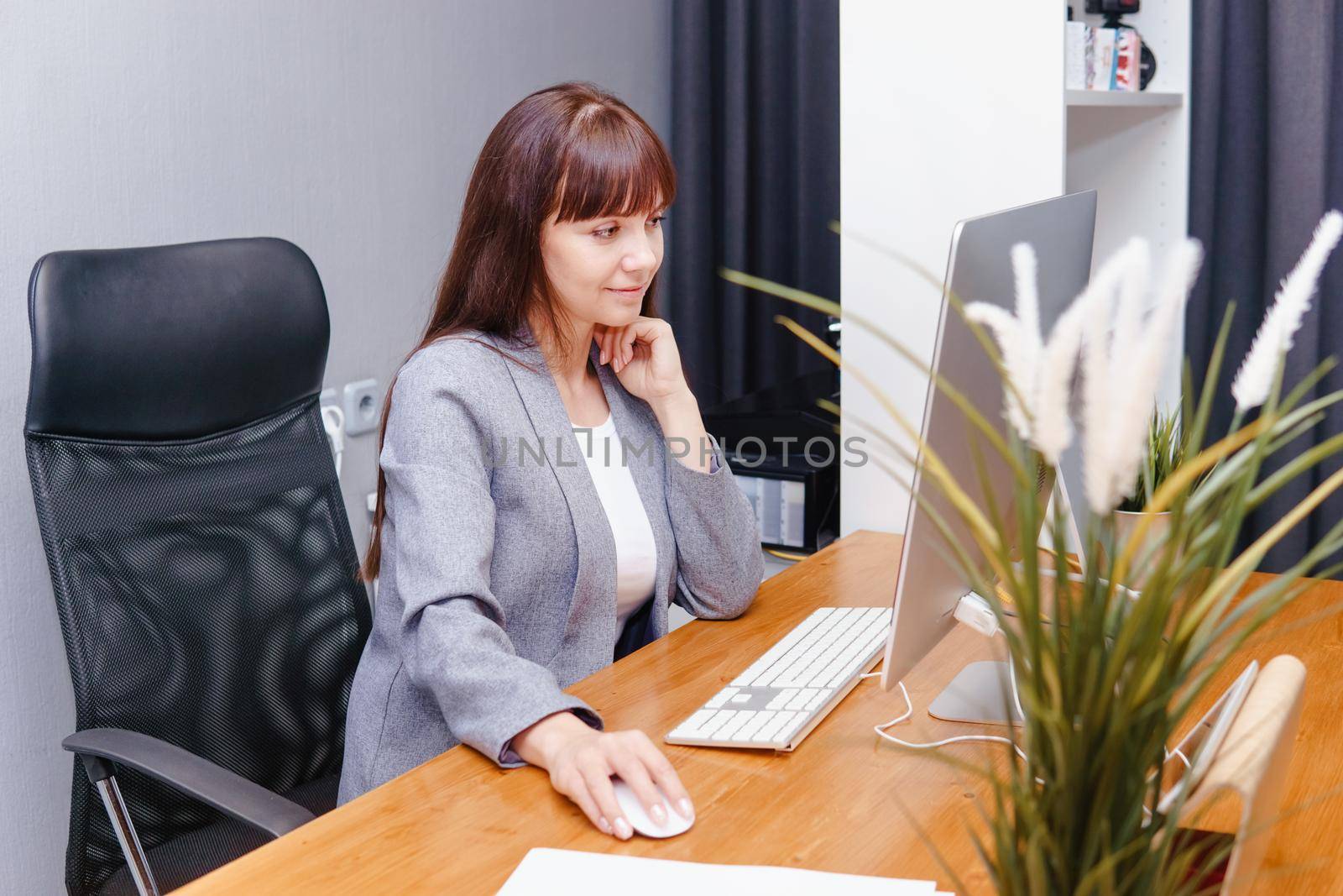 A brunette woman at a computer in the workplace. Business concept.