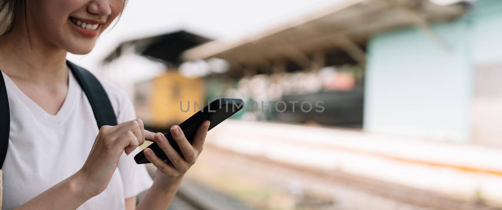 Close up hand of woman using smartphone at train station summer travel concept by nateemee