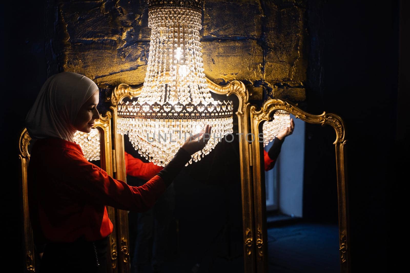 Fashion muslim model near big expensive chandelier. Islamic religion. Girl near mirrors