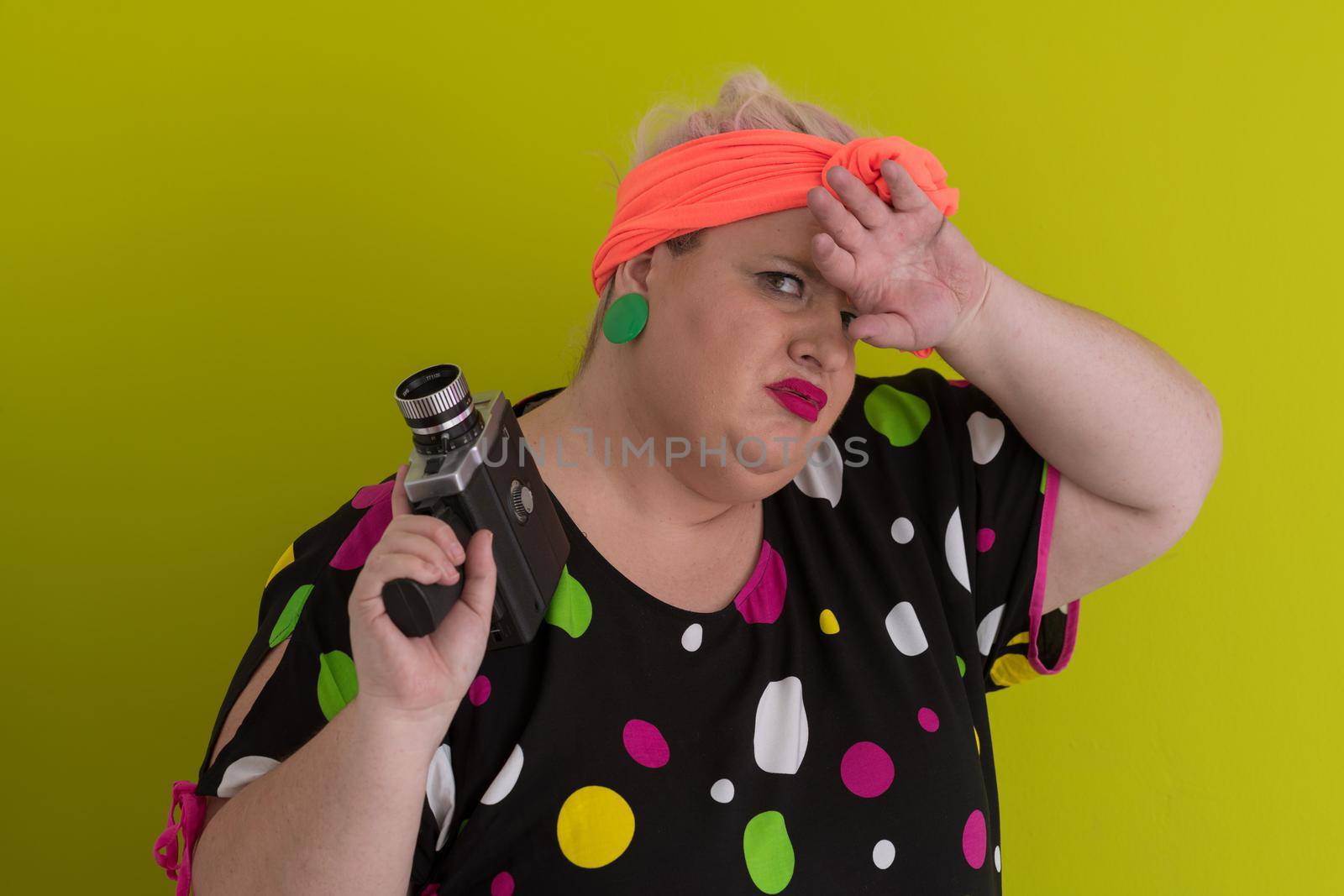 plus size smiling woman with funny emotional face expression with vintage camera in dress isolated on green background, traveler on vacation, summer fashion style, excited tourist. High quality photo