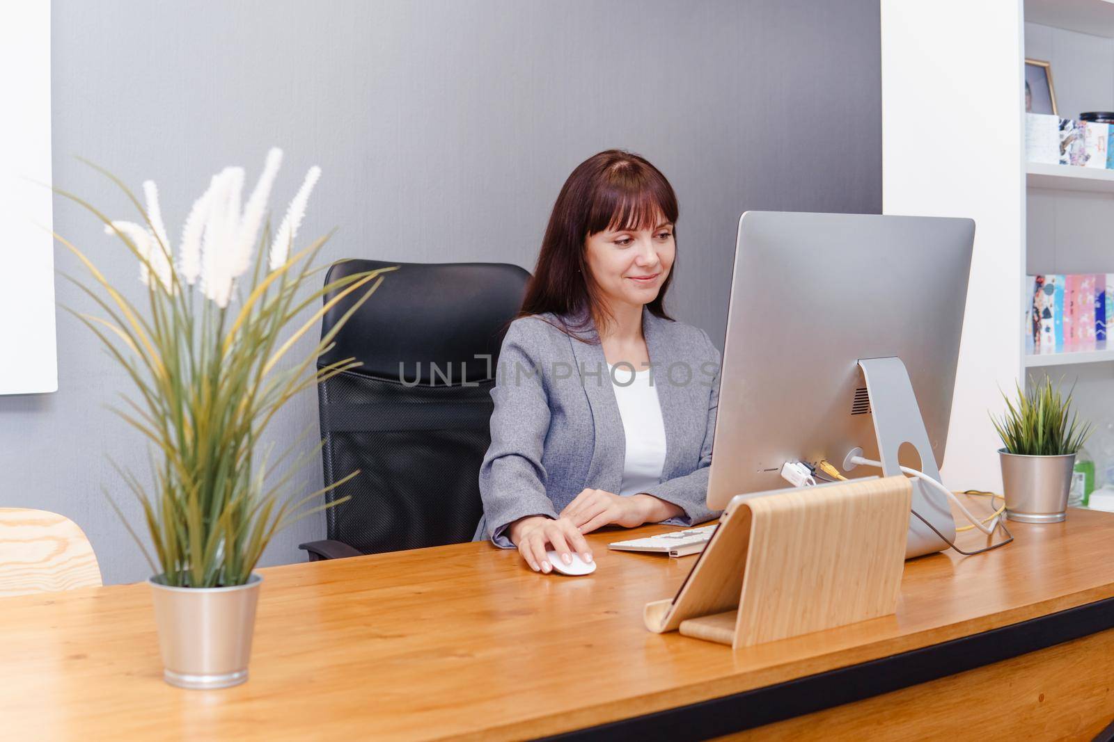 A brunette woman at a computer in the workplace. Business concept.