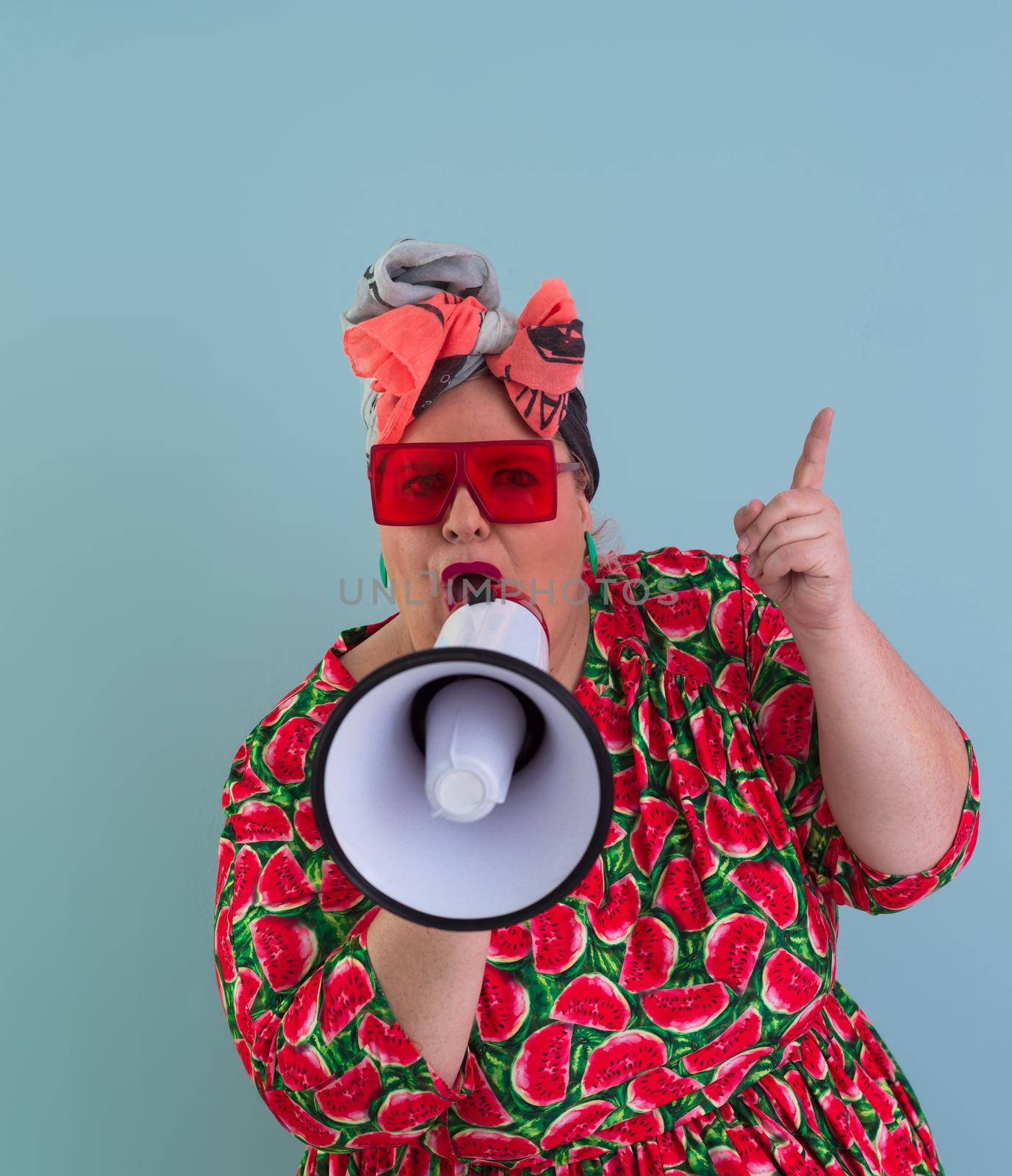Funny plus size woman posing isolated on cyan background studio portrait. Screaming in a megaphone. People emotions lifestyle concept. Mock up copy space. High quality photo