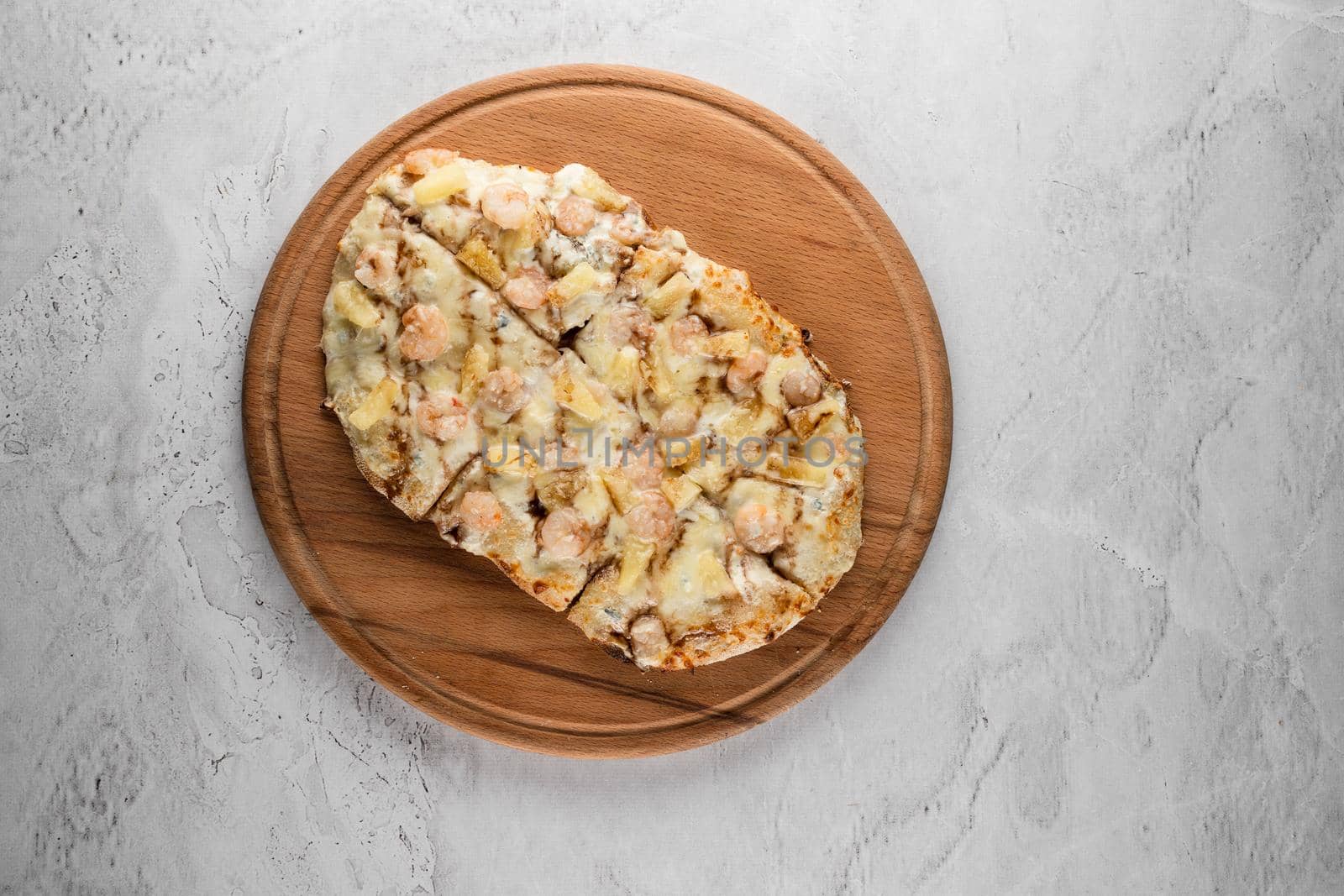 Pinsa romana with shrimps and pineapple on wooden plate on white background. Seafood scrocchiarella