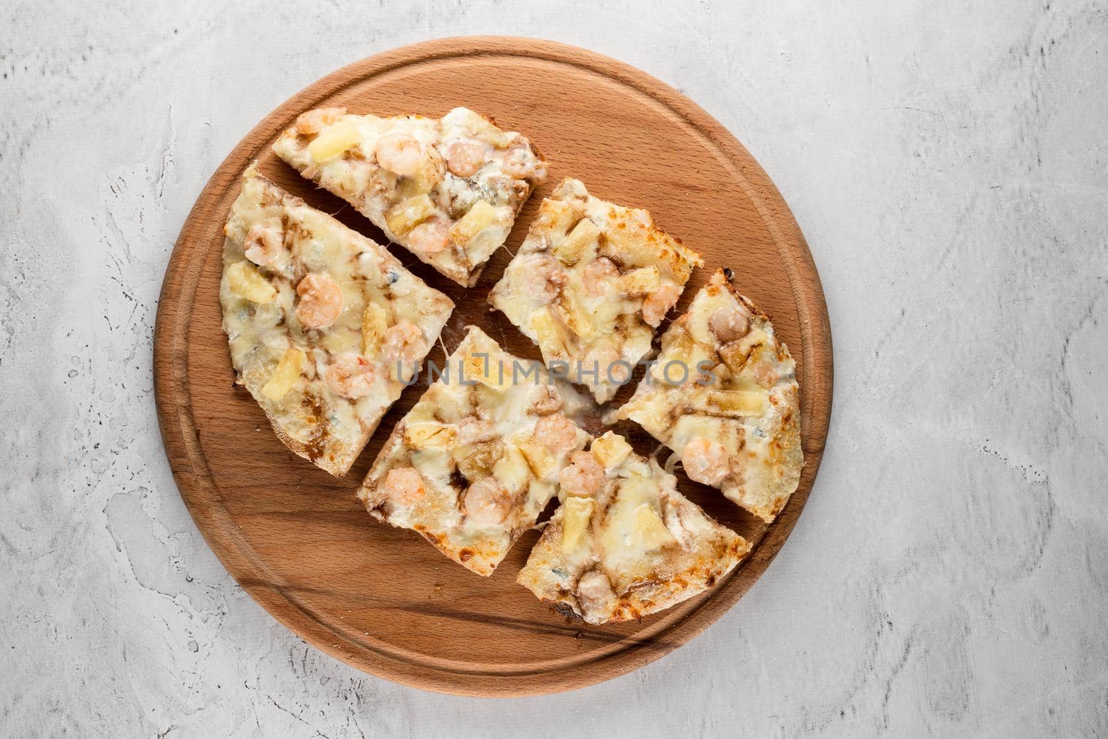 Pinsa romana with shrimps and pineapple on wooden plate on white background. Seafood scrocchiarella