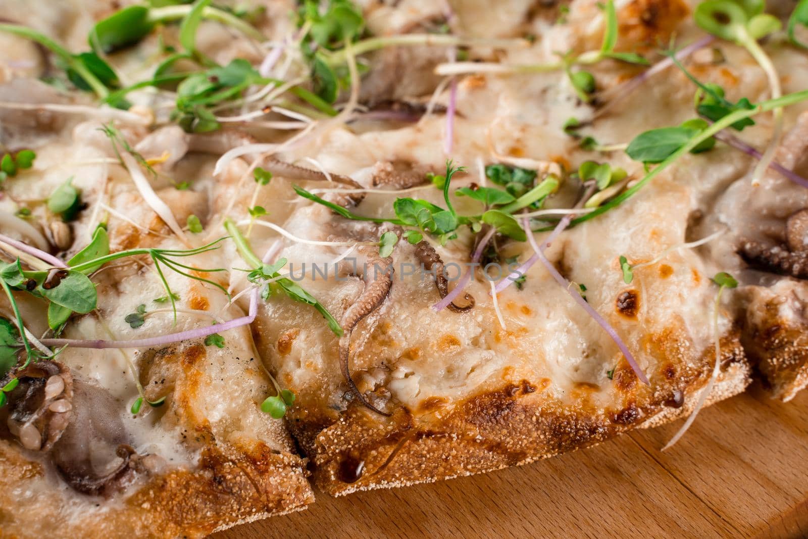 Pinsa romana with octopus seafood, cheese, microgreen. Italian gourmet cuisine. Scrocchiarella