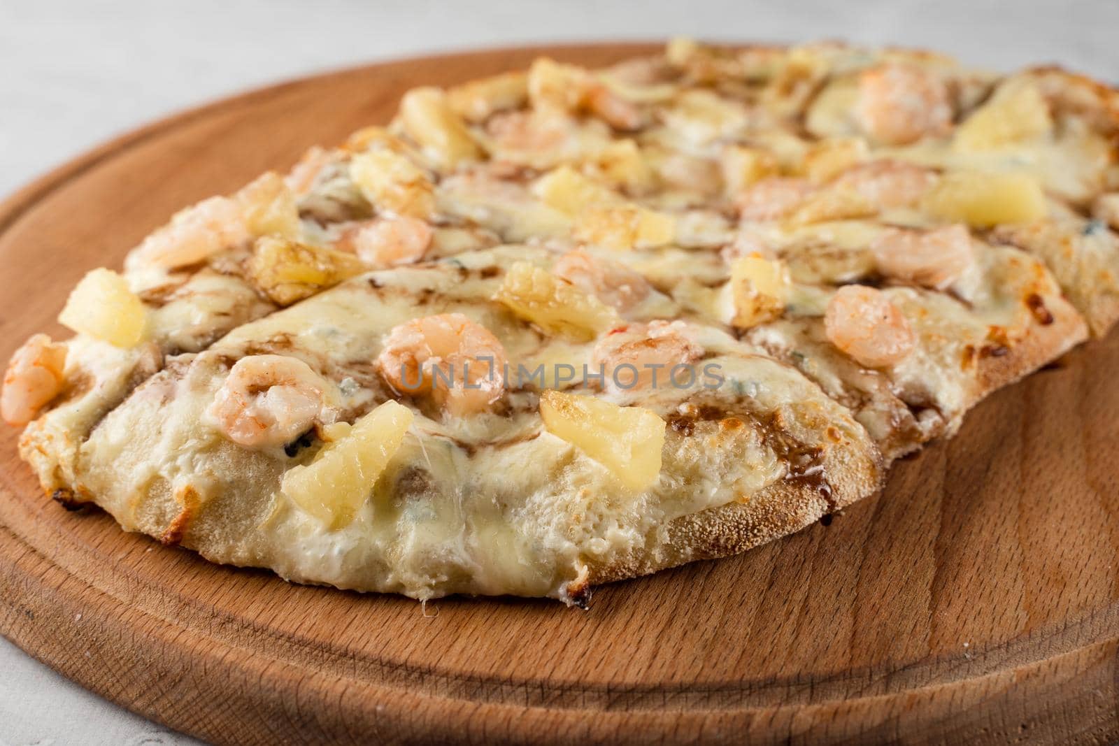 Pinsa romana with shrimps and pineapple on wooden plate on white background. Seafood scrocchiarella