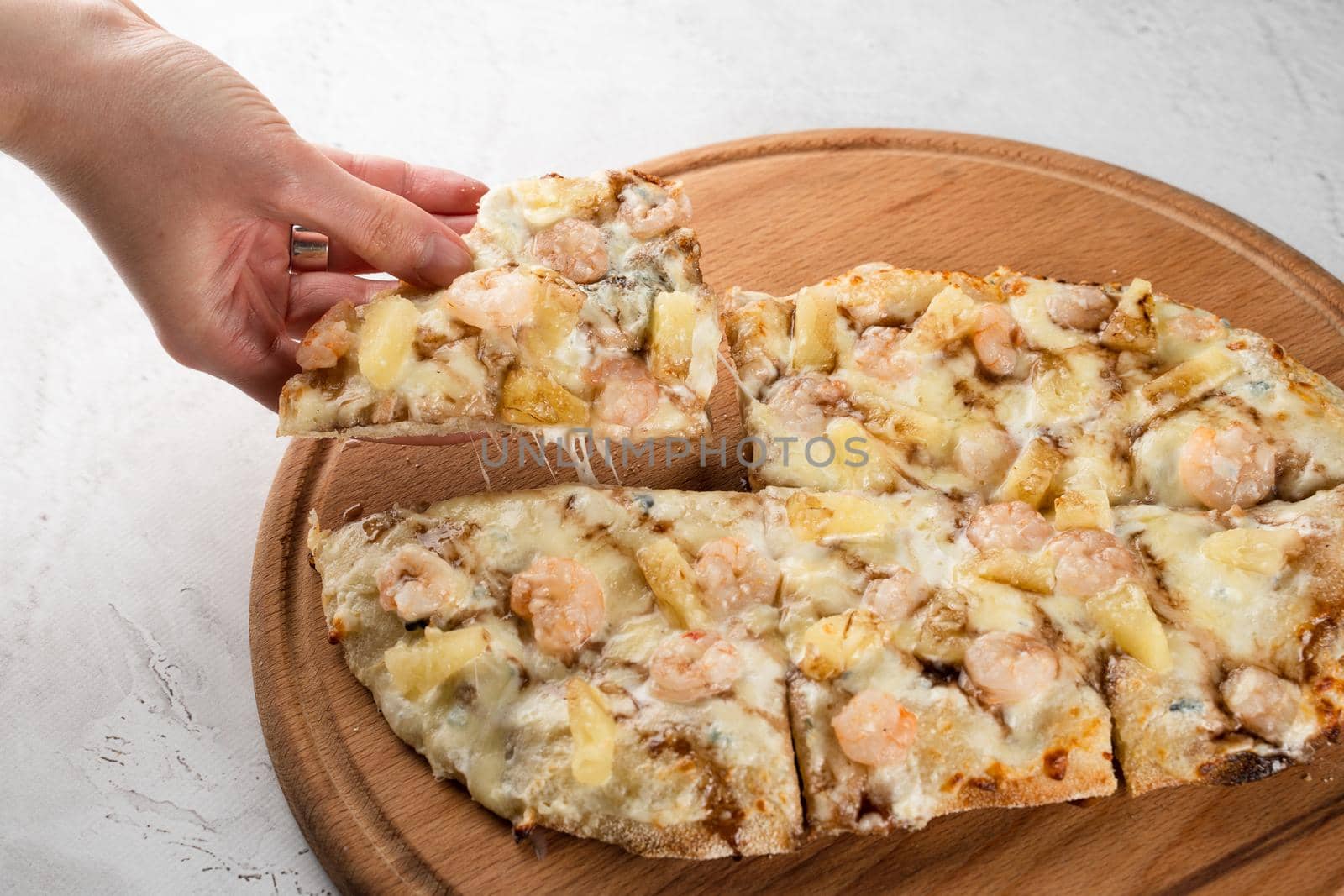 Pinsa romana with shrimps and pineapple on wooden plate on white background. Seafood scrocchiarella