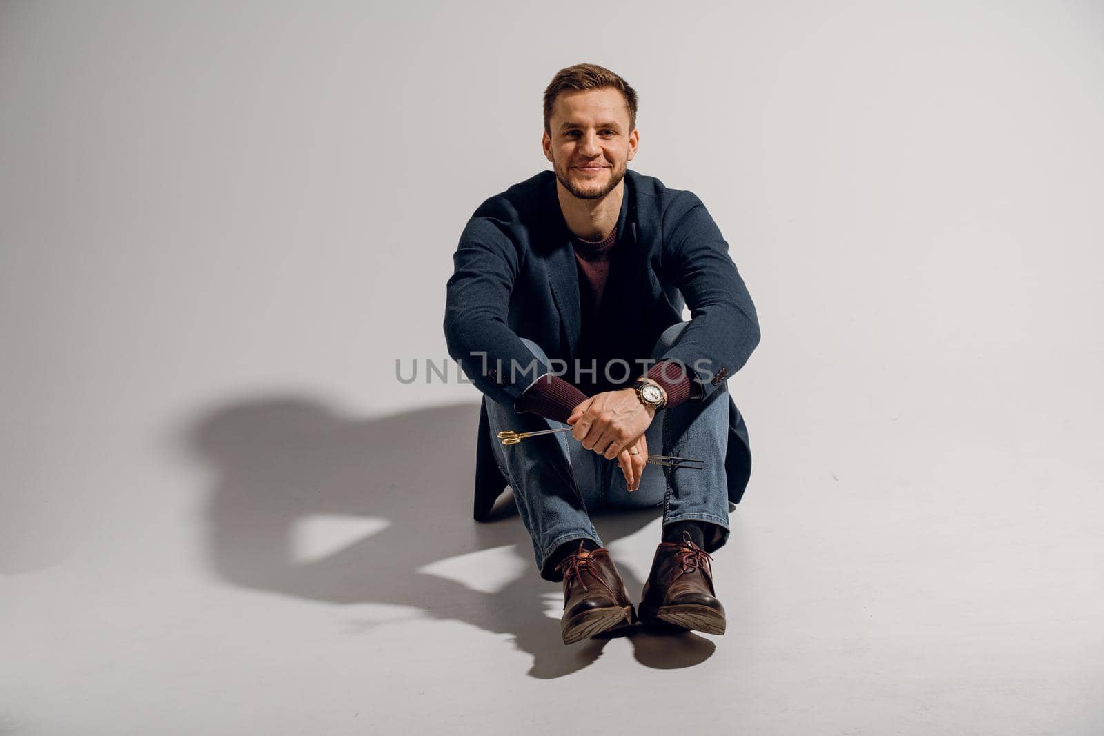 Doctor with surgical equipment needle and scissors. Handsome man weared casual business suit. Portrait of surgeon in studio