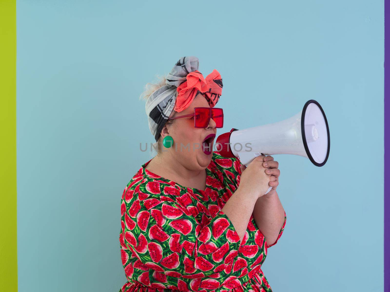 Funny plus size woman posing isolated on cyan background studio portrait. Screaming in a megaphone. People emotions lifestyle concept. Mock up copy space. High quality photo