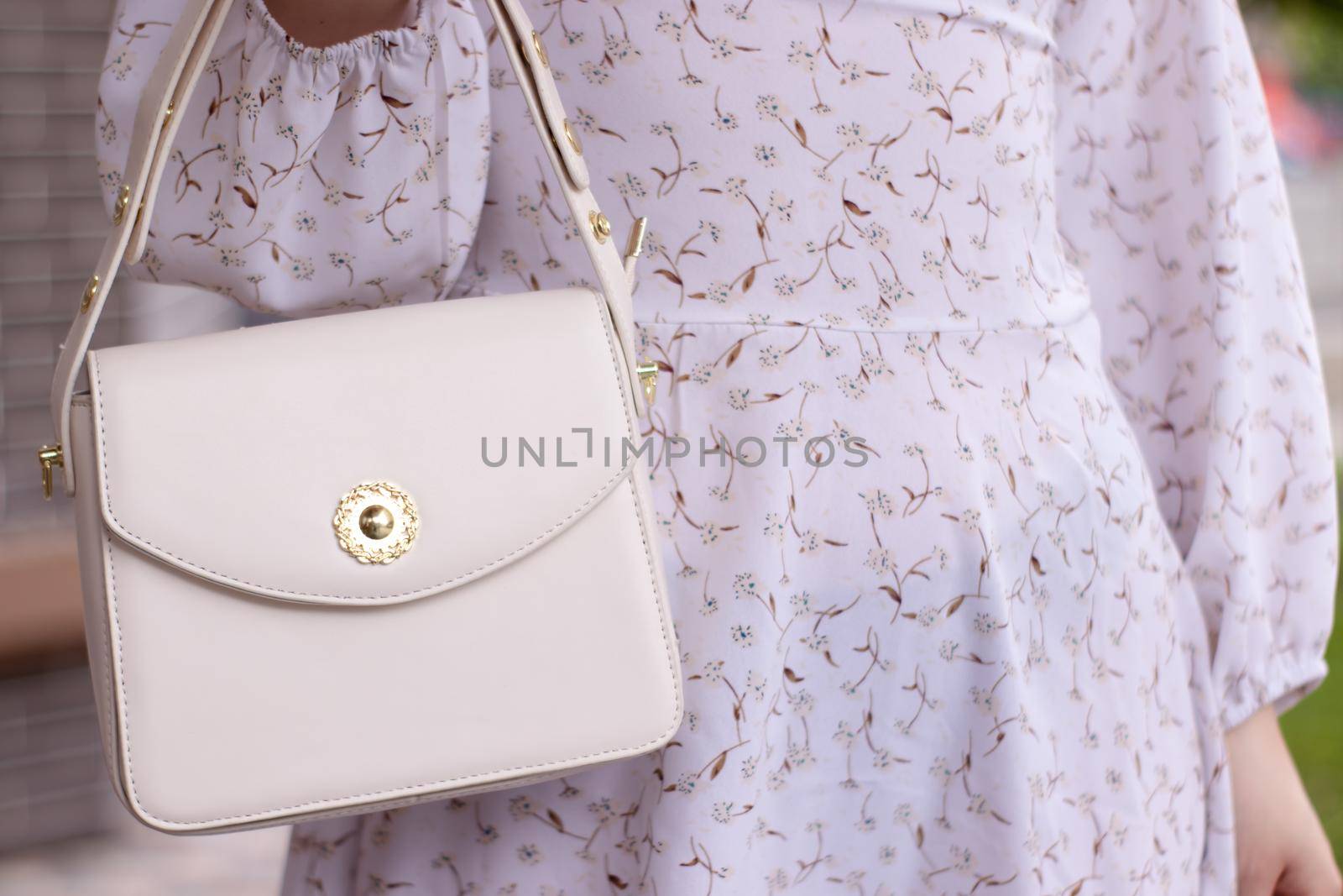 close up of woman in white dress holding fashionable beige purse outside. Product photography. stylish handbag for women by oliavesna