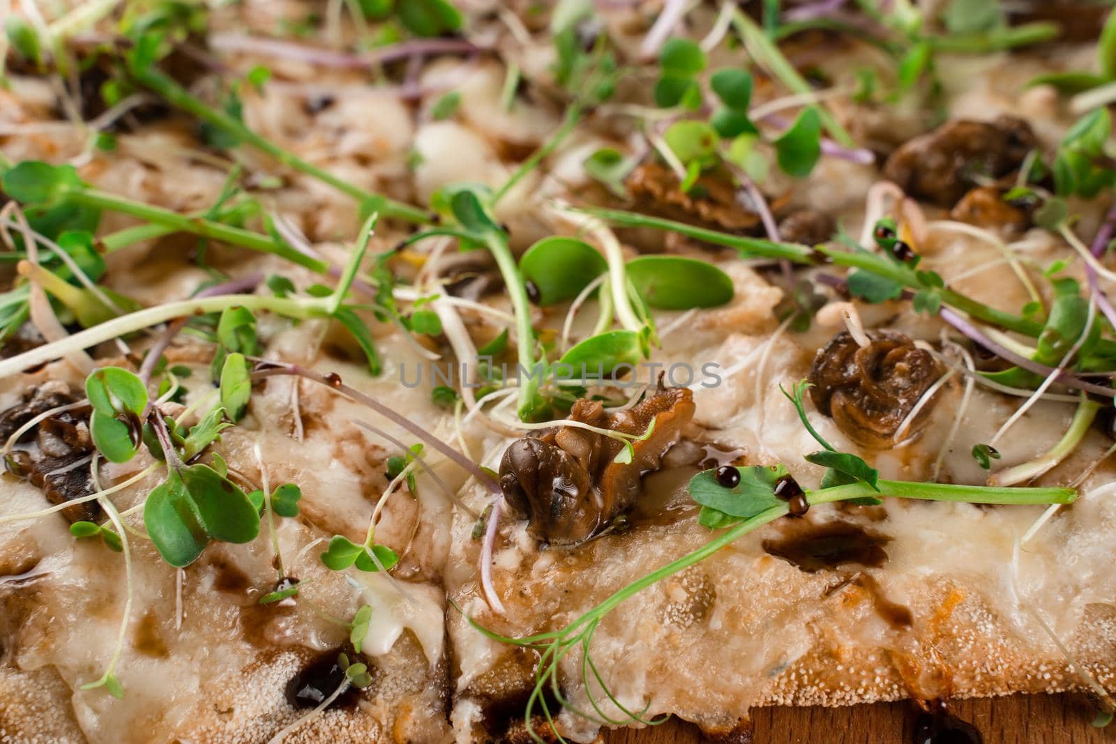 Italian pinsa romana with french escargot grape snails on dark background close-up. Pinsa with snail, cheese, microgreen. Italian gourmet cuisine.