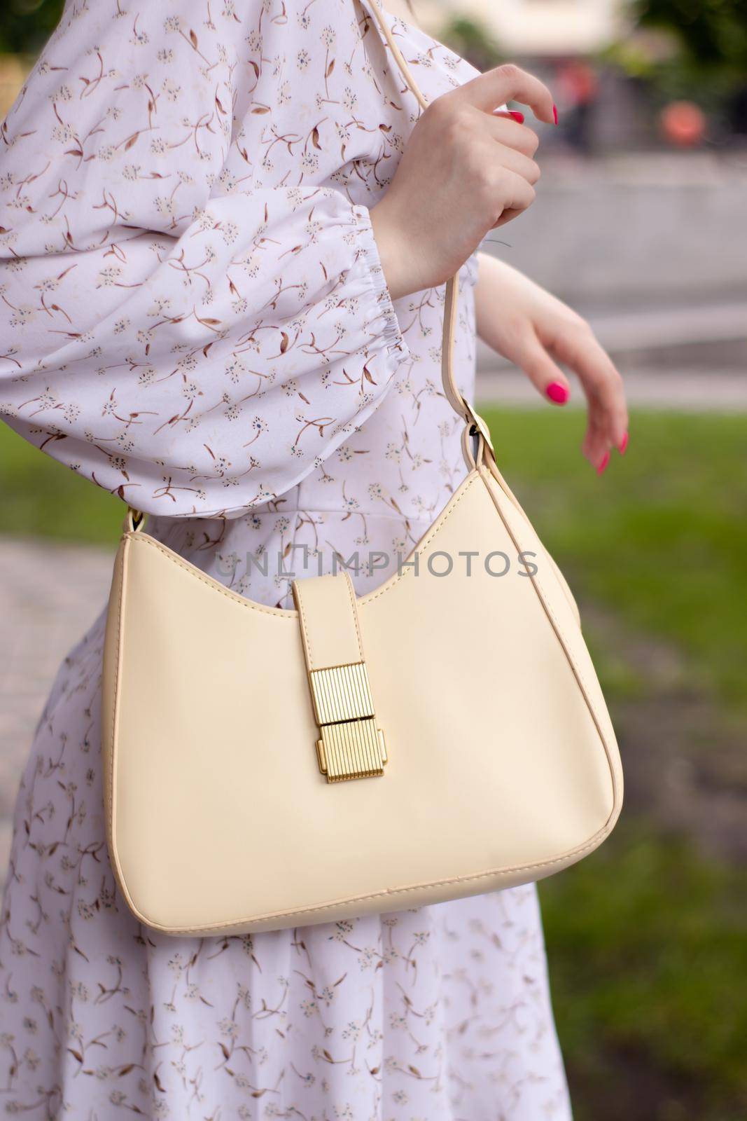 close up of woman in white dress holding fashionable beige purse outside. Product photography. stylish handbag for women by oliavesna