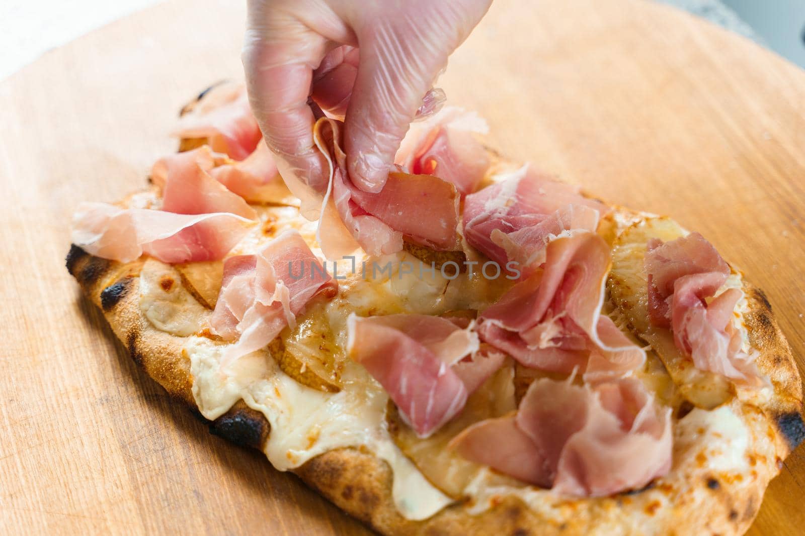 Chef cooking pinsa romana with pear, cheese, prosciutto in delivery box. Scrocchiarella gourmet italian cuisine