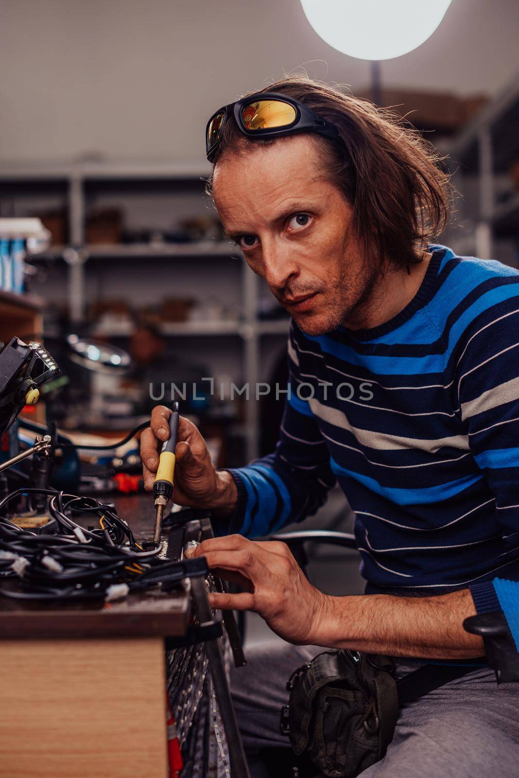 Industrial worker man soldering cables of manufacturing equipment in a factory. Selective focus. High-quality photo
