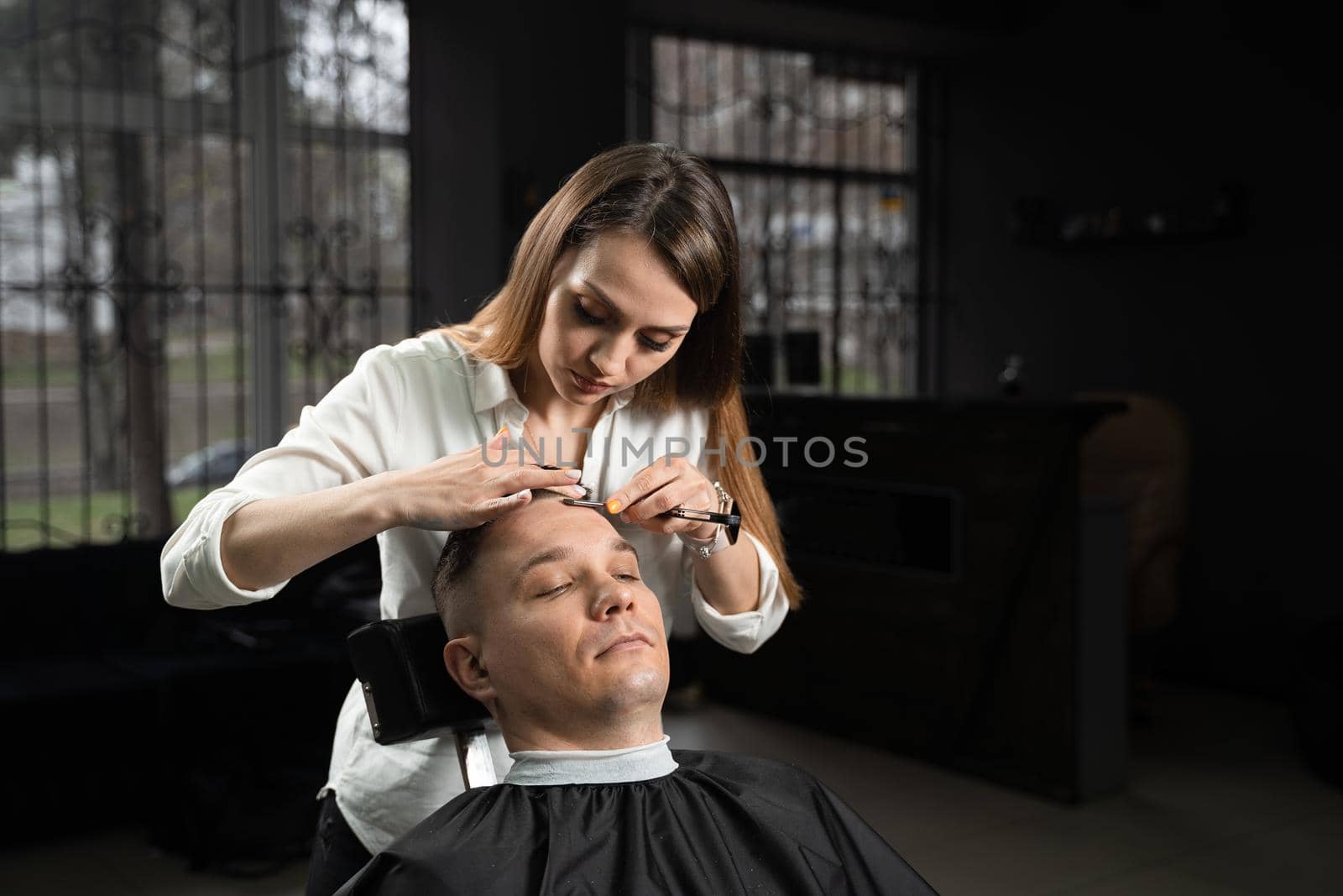 Straight razor cut man hair in barbershop. Attractive woman barber making hairstyle for handsome man